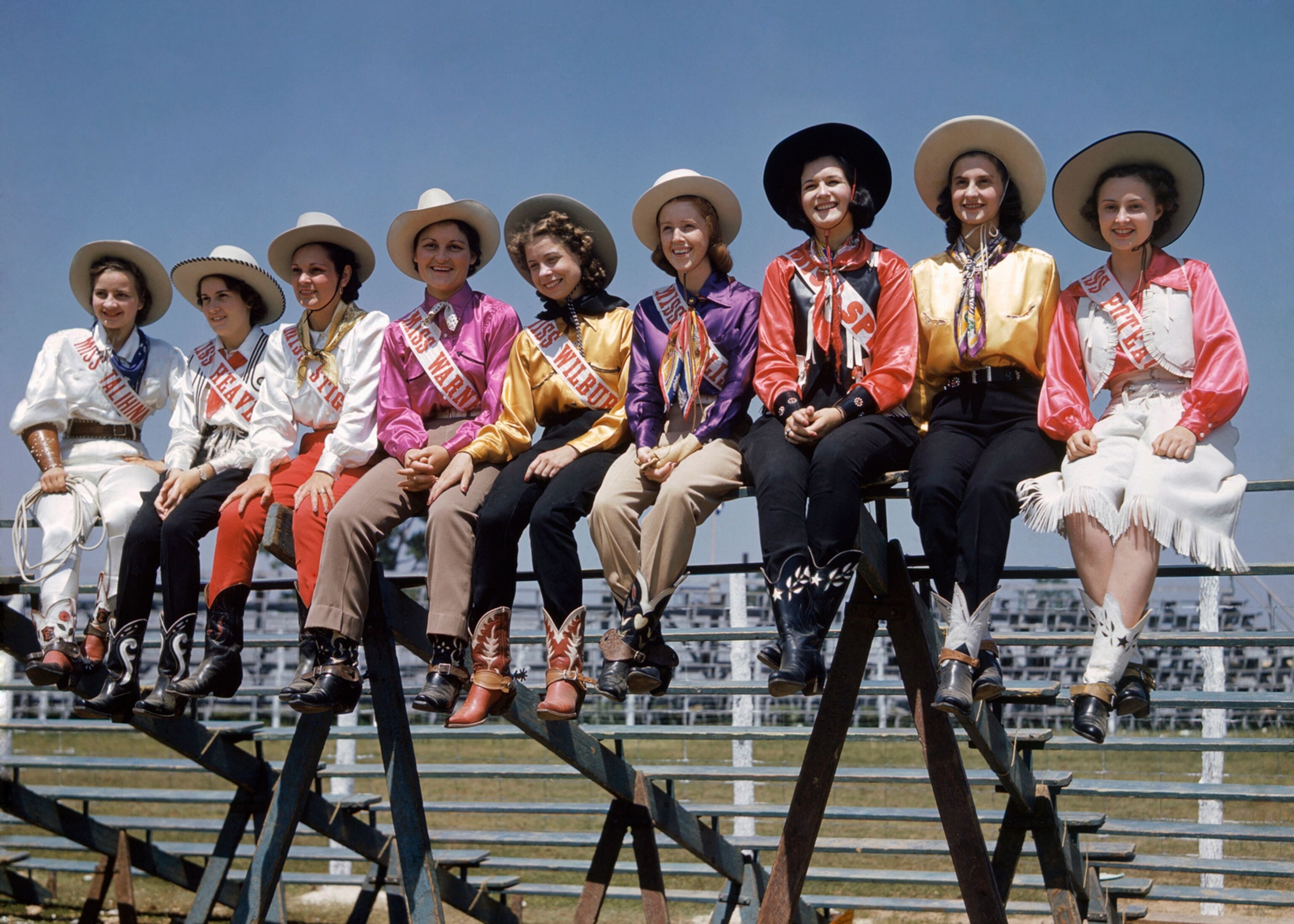 Oklahoma's cowgirl team siting on a fence at the Fort Smith competition
