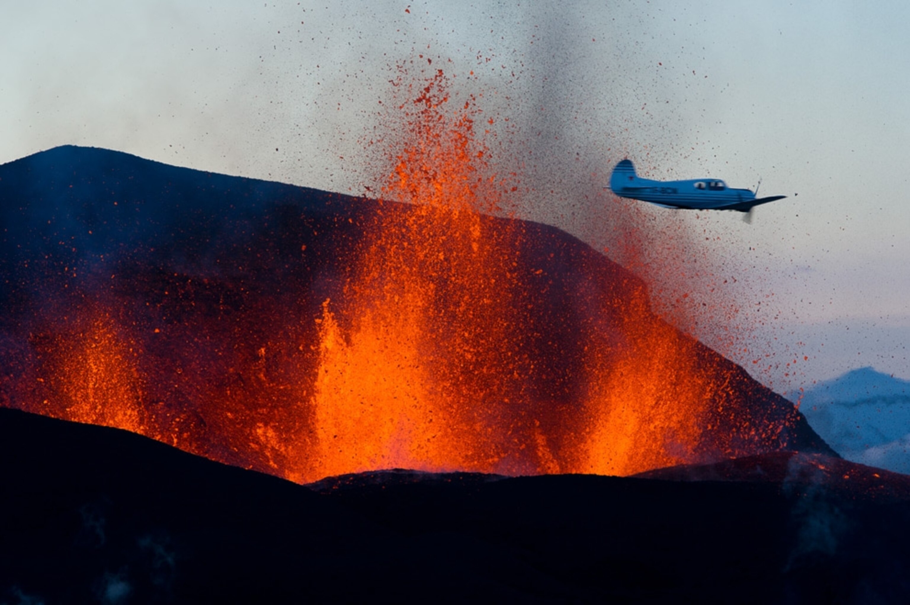 A small airplane cruises by a burst of lava coming from Iceland's Eyjafjallajökull volcano in a picture.