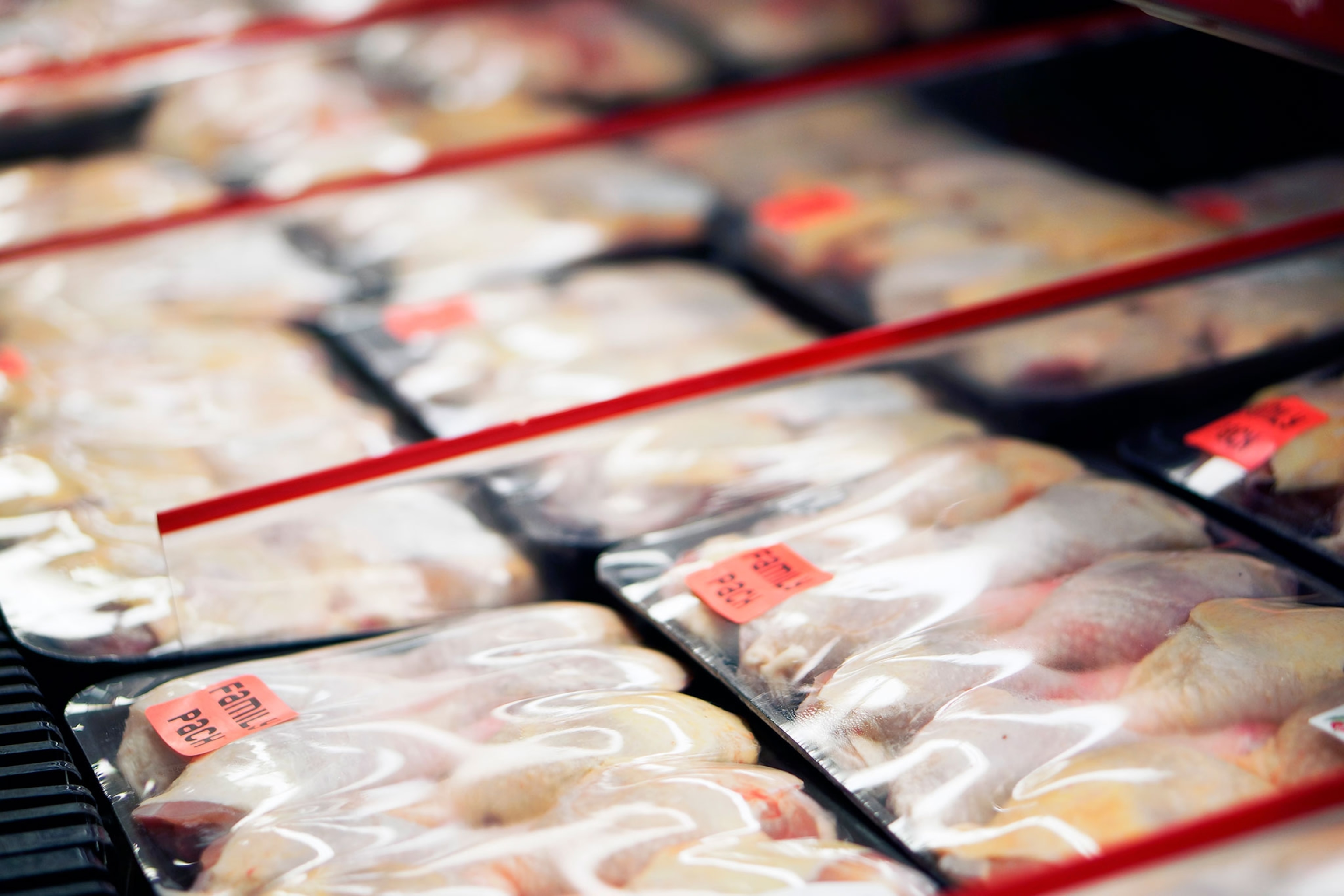 packages of raw chicken in a grocery store refrigerator