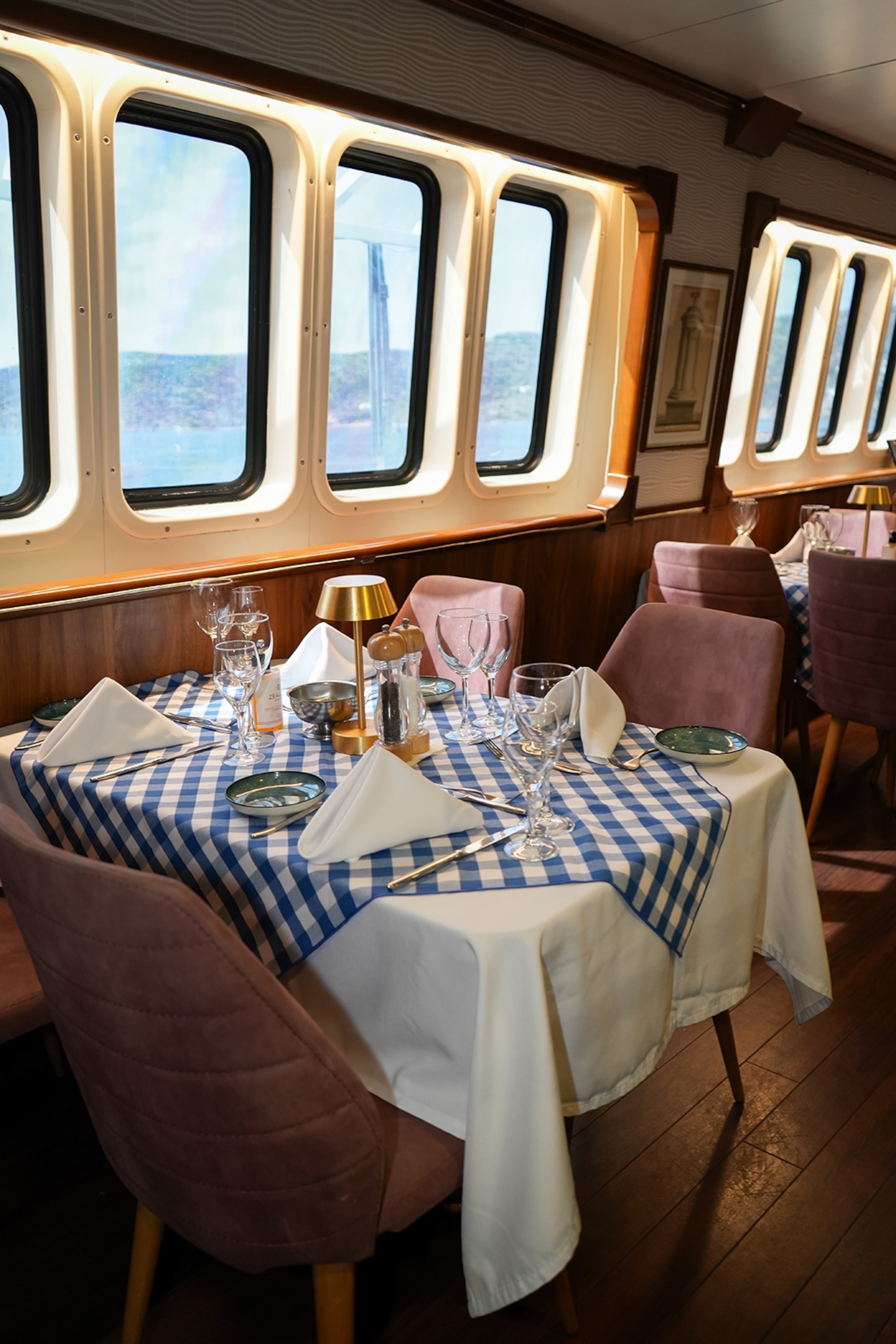 The modern, quirky interiors of a dining room in a small boat cruise, featuring linen-decked tables and a formal tablescape.