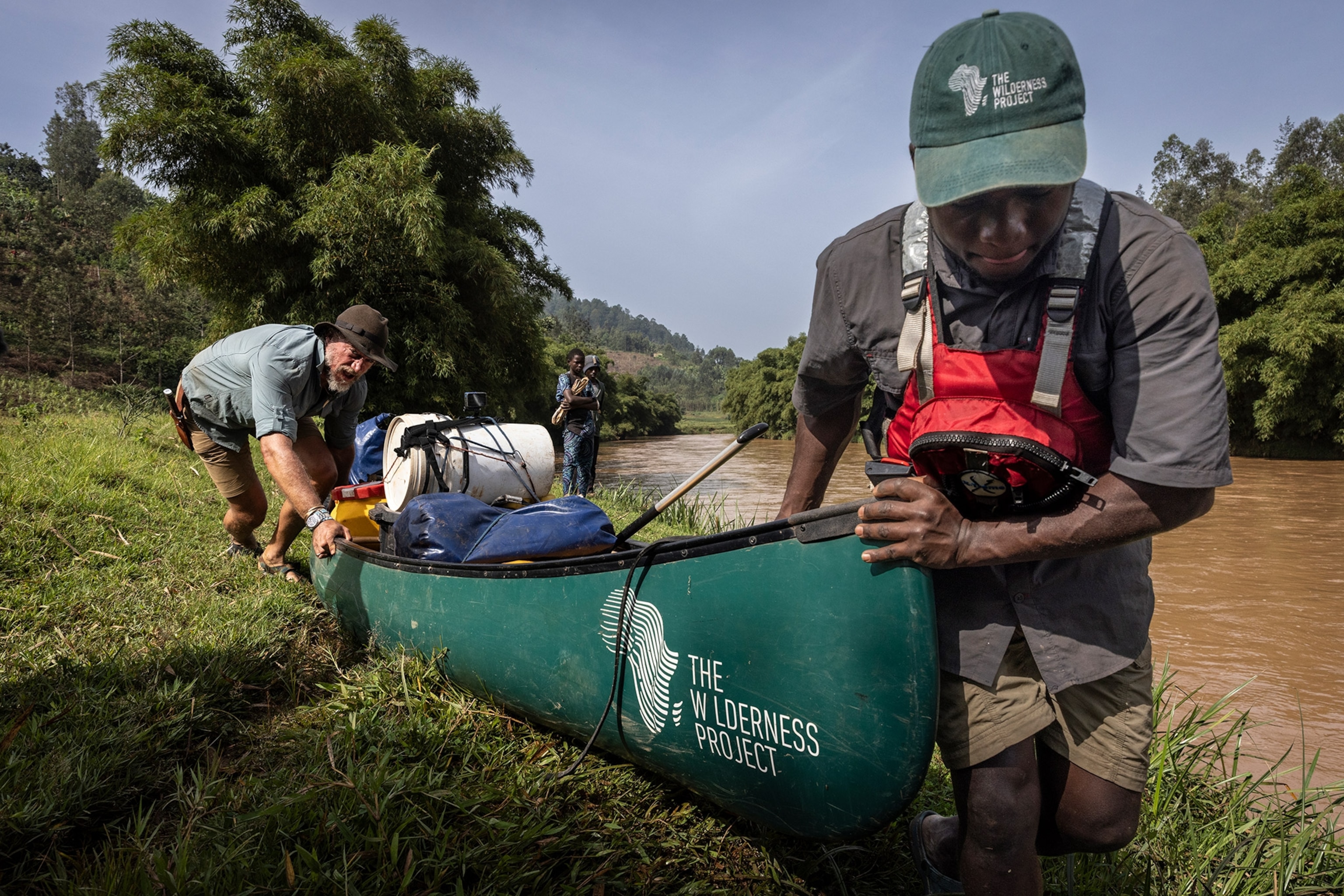 two people pushing a loaded canoe through shallow water