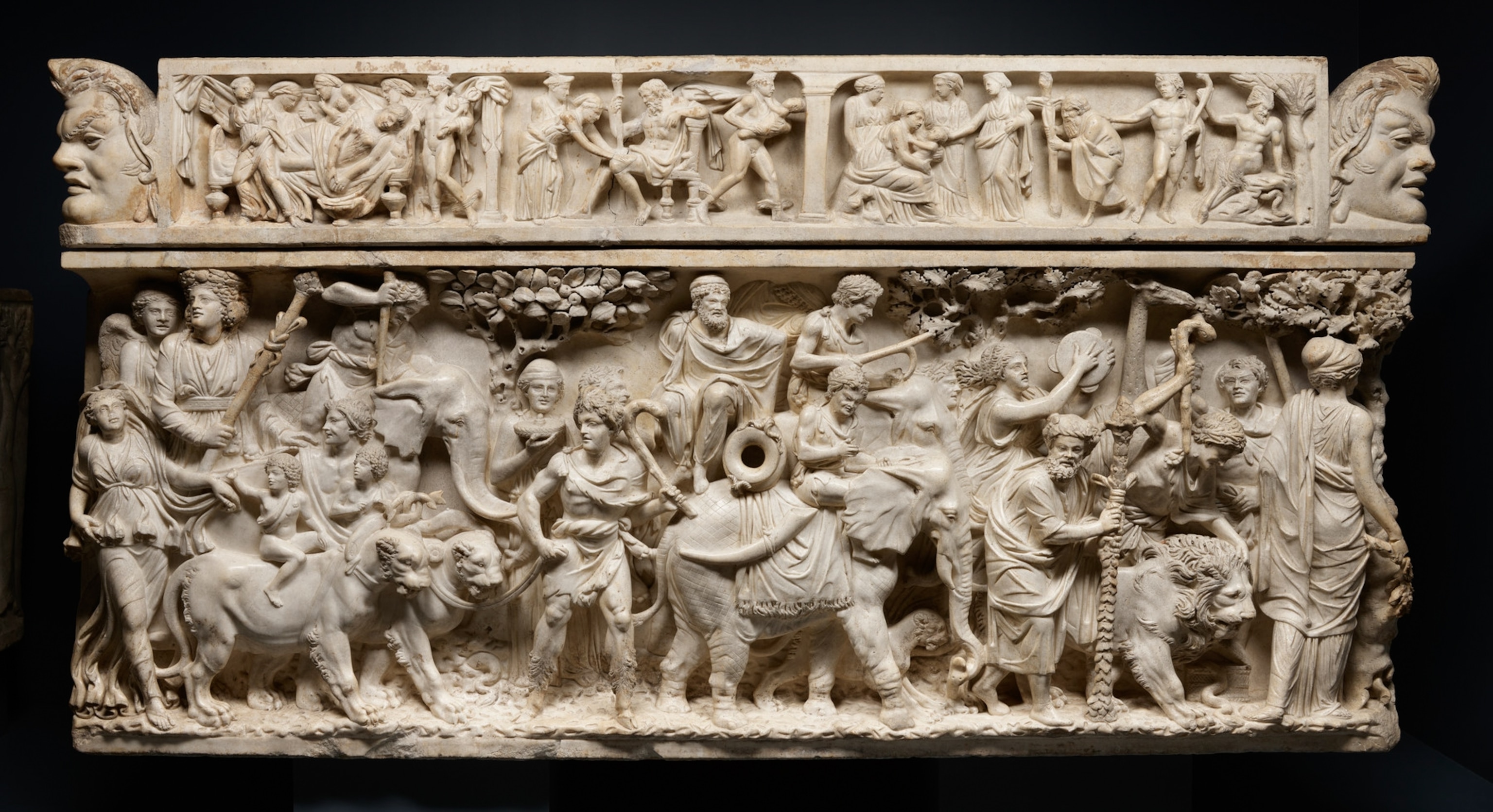 An intricately carved marble Roman sarcophagus depicts people, animals, and mythological scenes in detailed relief across its surface.