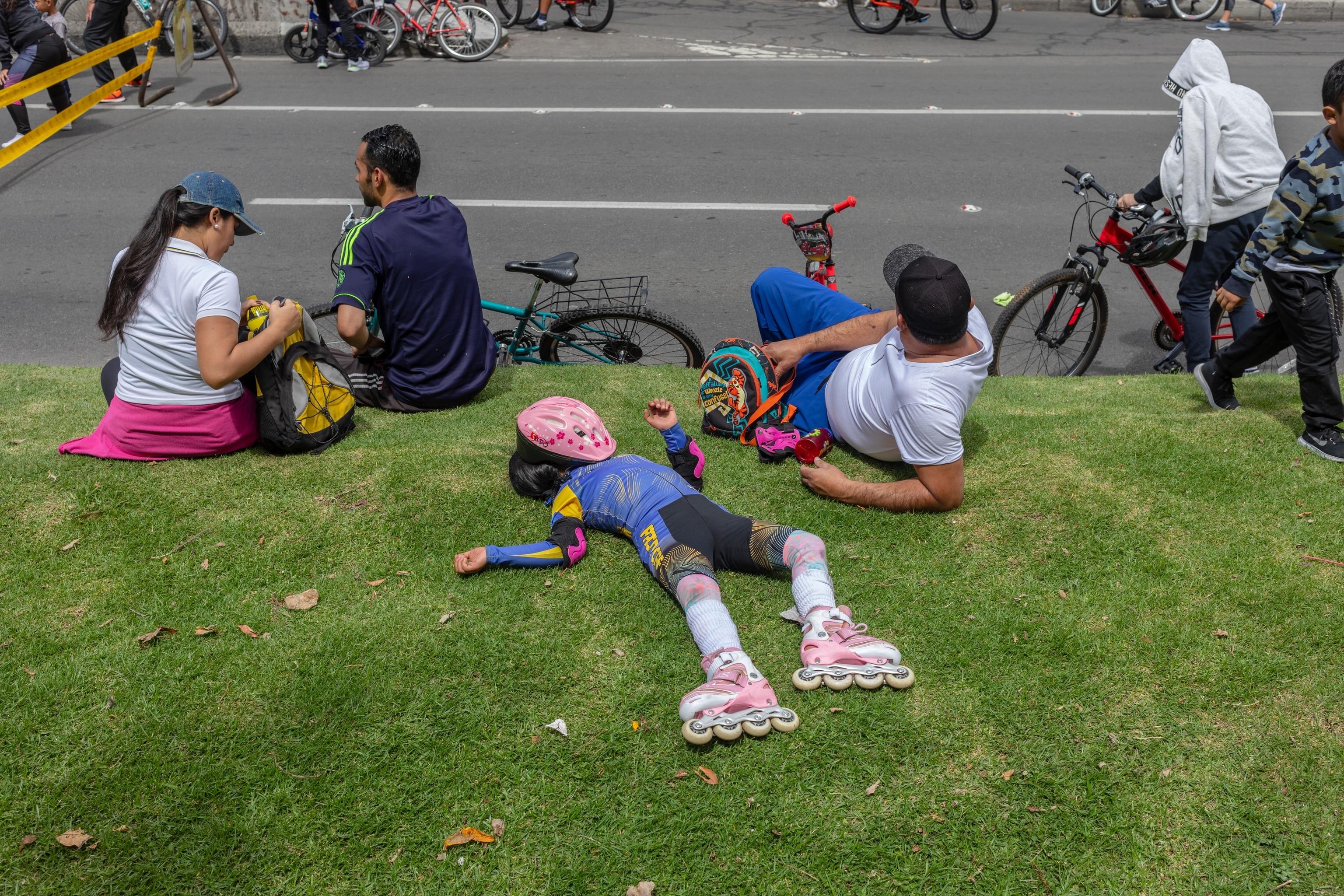 A child lies on the grass wearing roller blades.