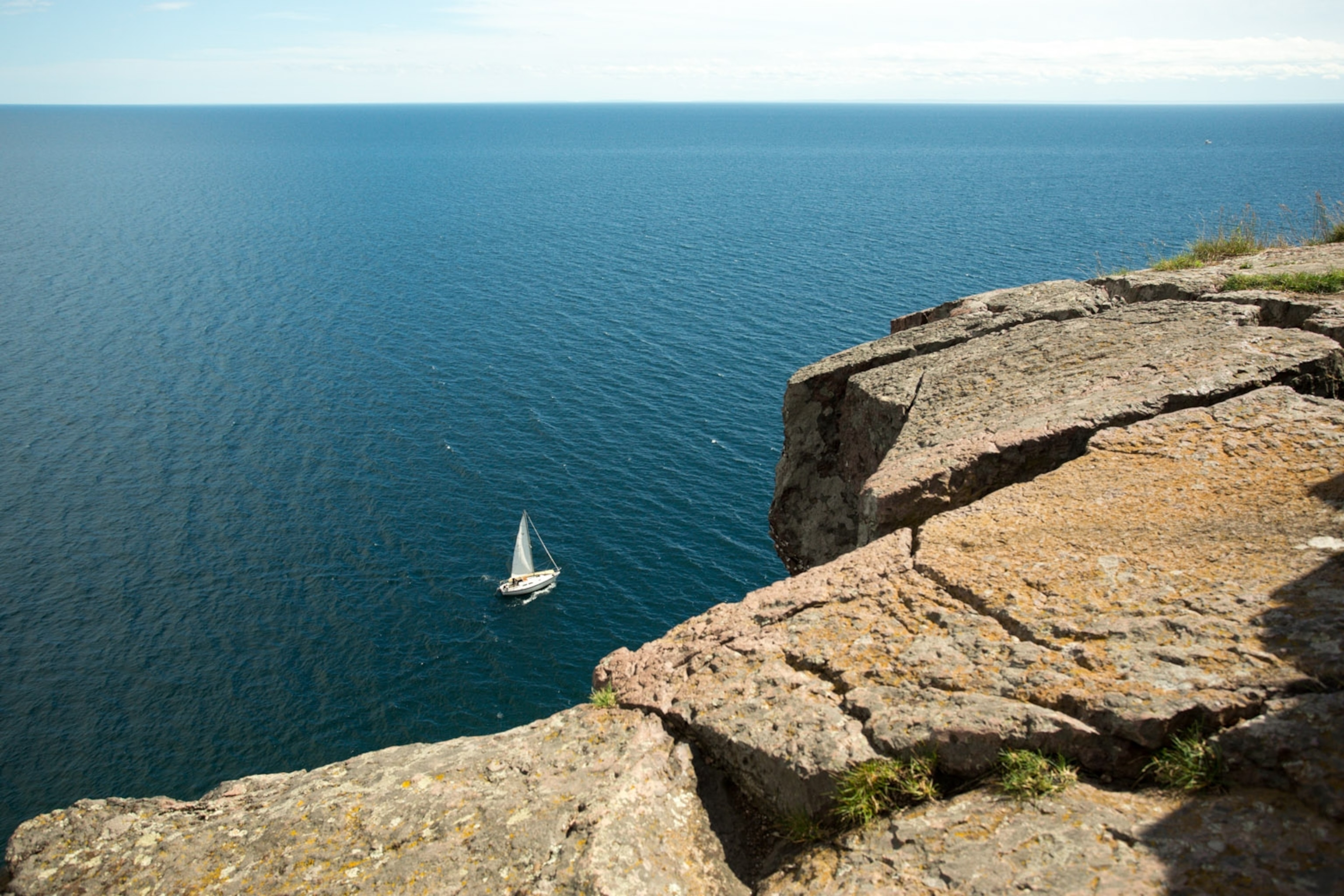 Dave and Amy Freeman sail along the North Shore of Lake Superior with their 20 ft signature canoe lashed to the deck of their sailboat. Photo by: Nate Ptacek