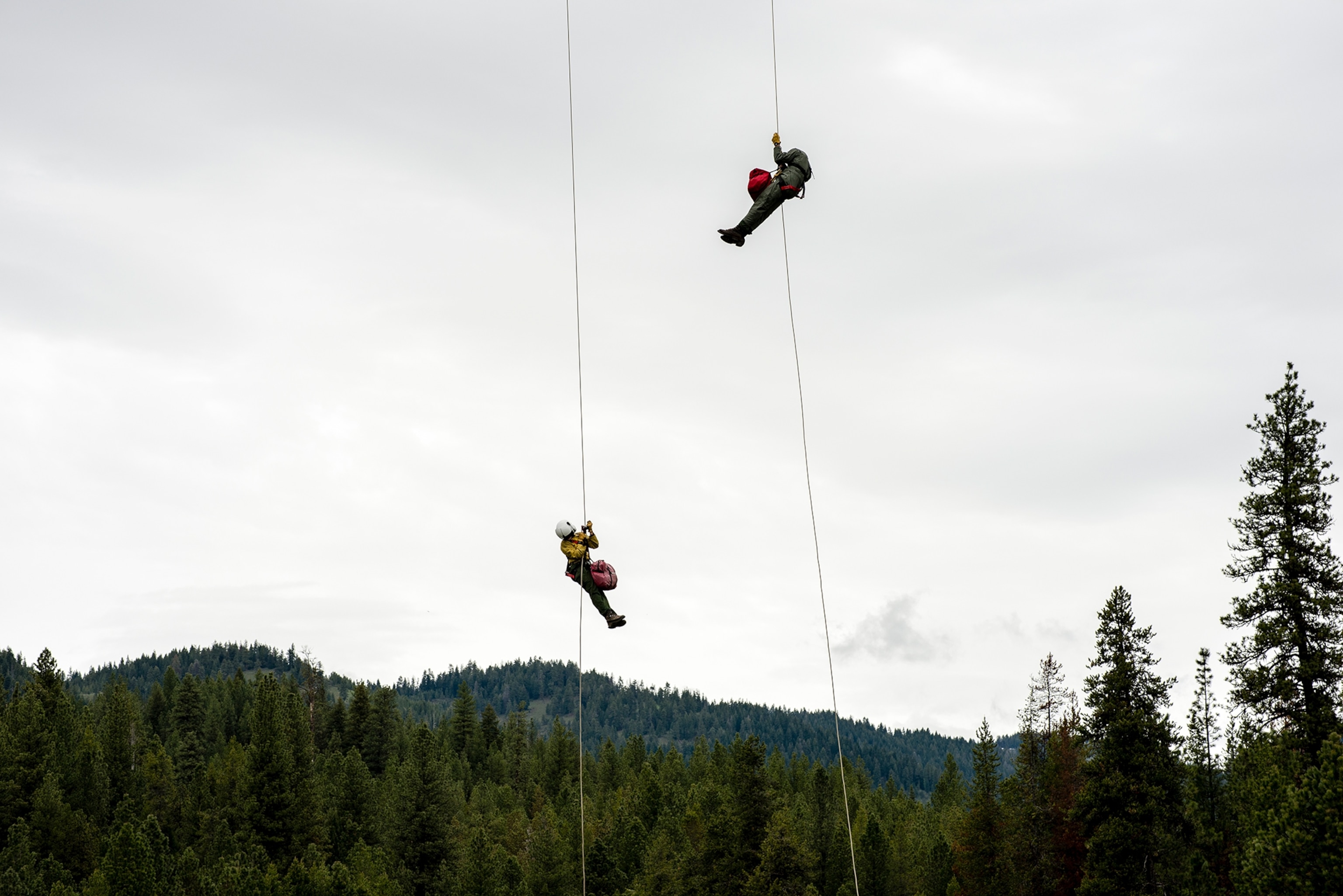 two crew members rappelling to the ground