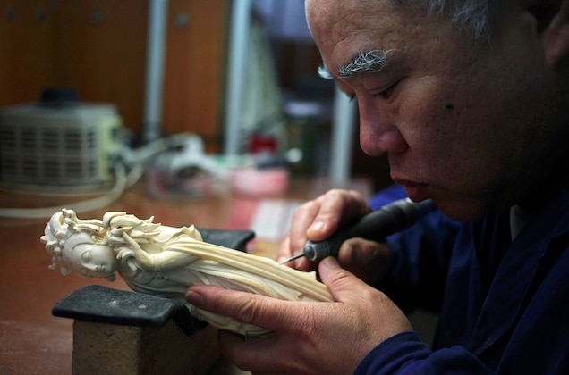 An artist carves an ivory sculpture in the Beijing Ivory Carving Factory. The government has not said what its plans are for ivory workshops once the ban on the ivory trade goes into effect. Photograph by How Hwee Young, EPA