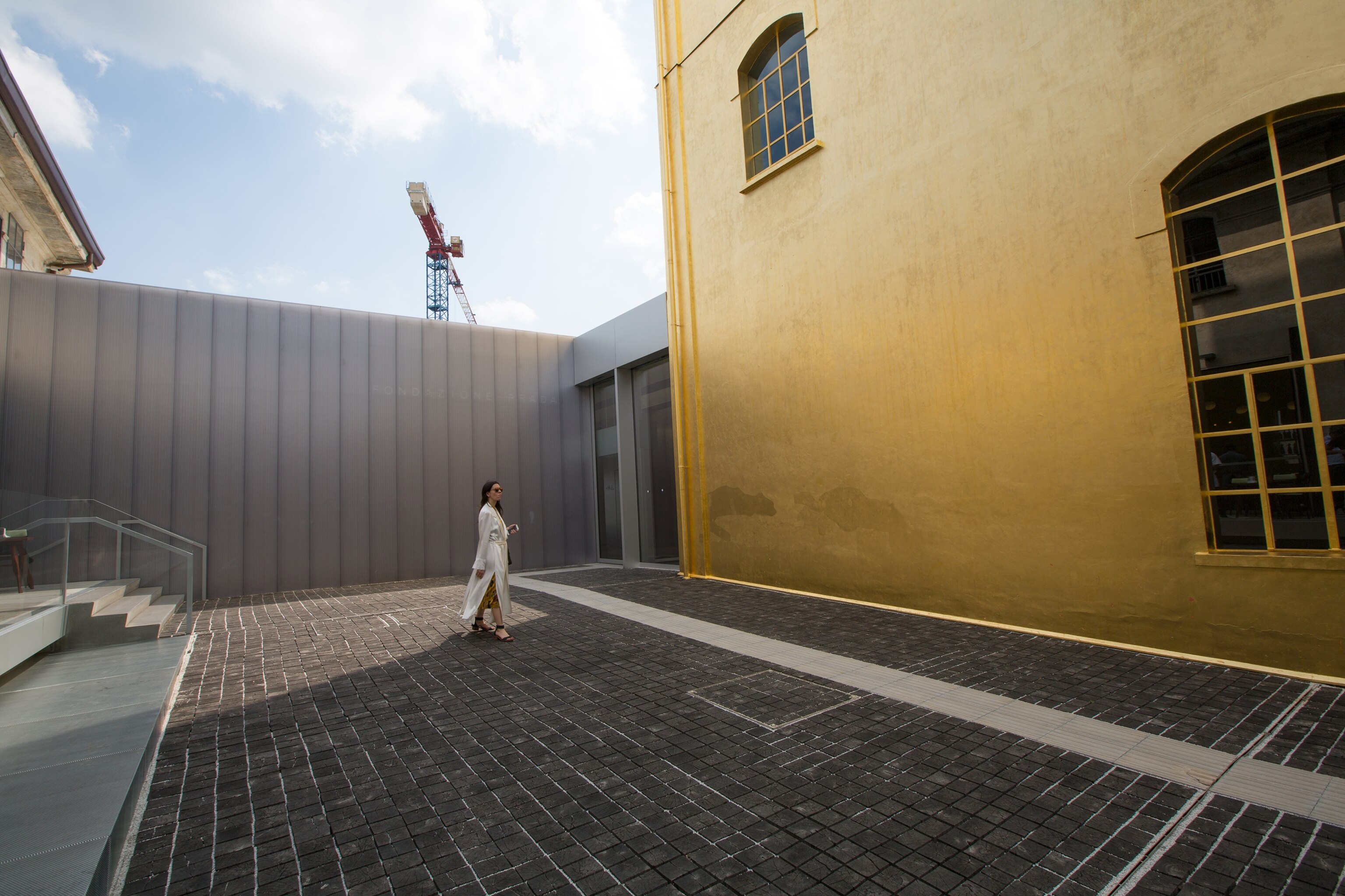a visitor in the entrance courtyard of the Fondazione Prada Milano in Milan, Italy