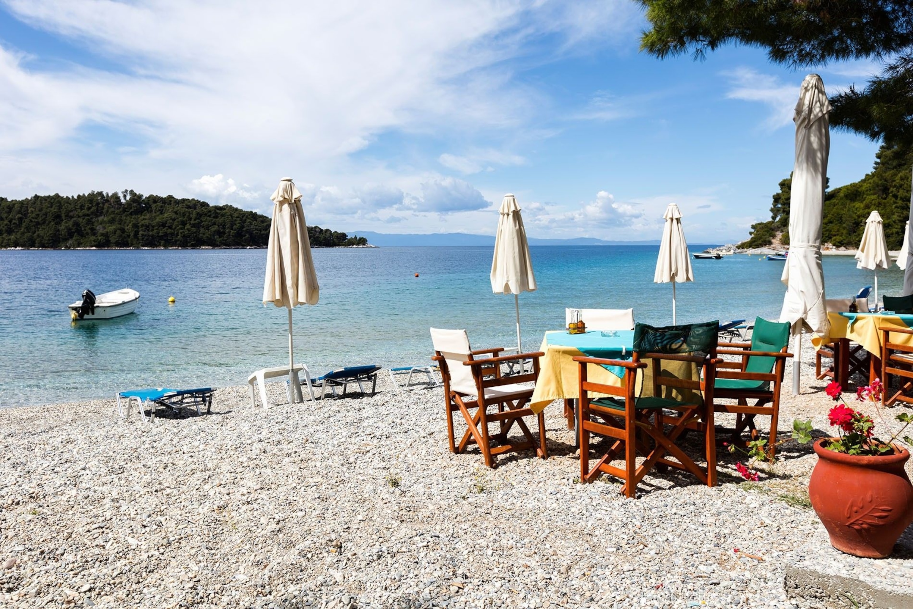 A beach populated by dining tables and sun loungers.