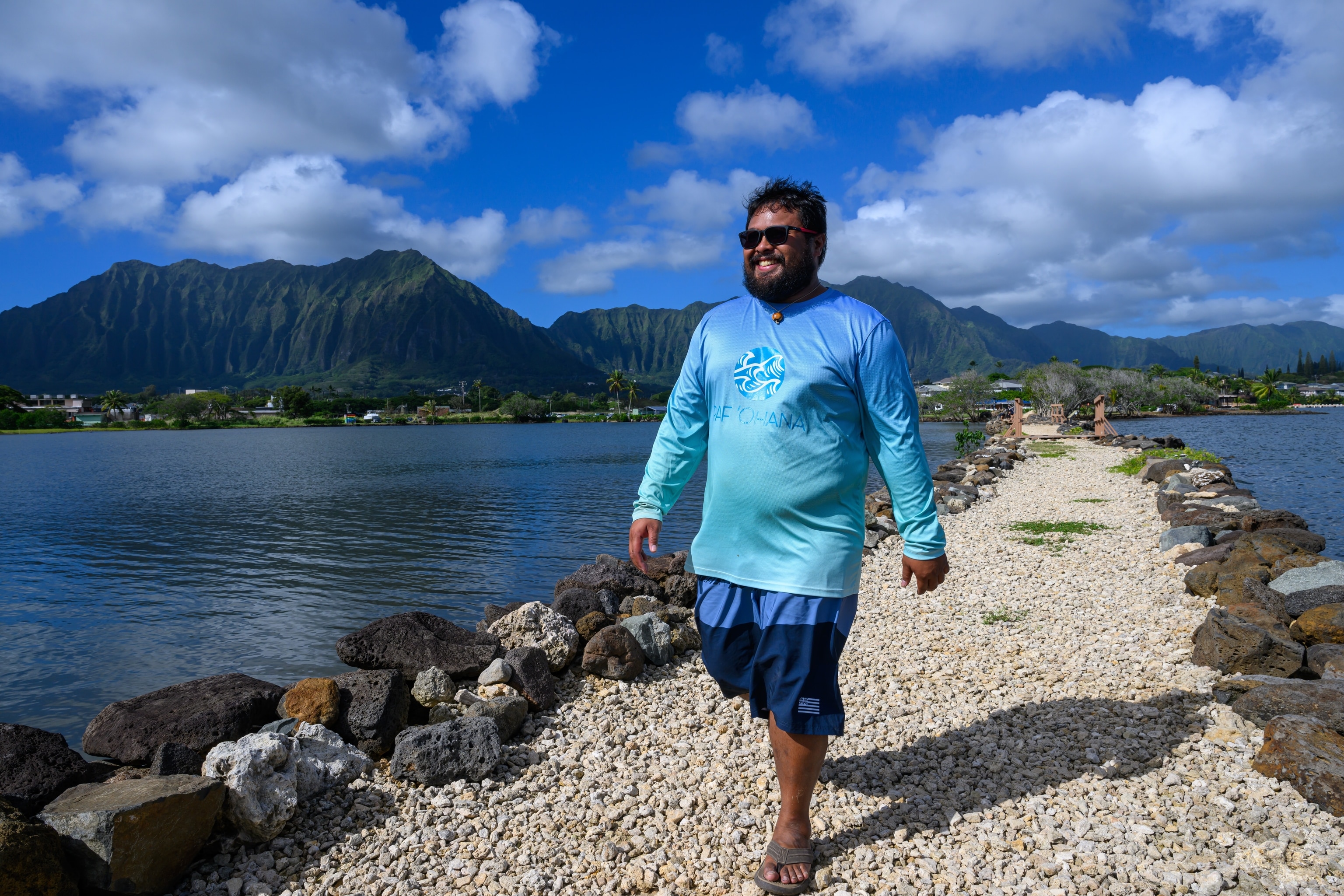 Jayten Galario walks along the sea wall separating a traditional fish pond from the open ocean.