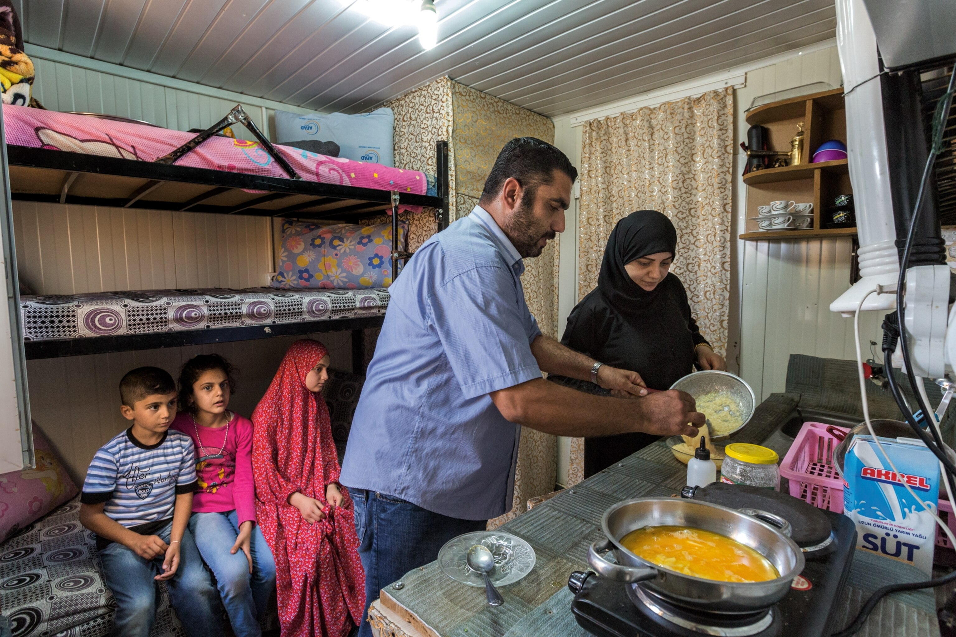 a refugee family cooking inside a container home