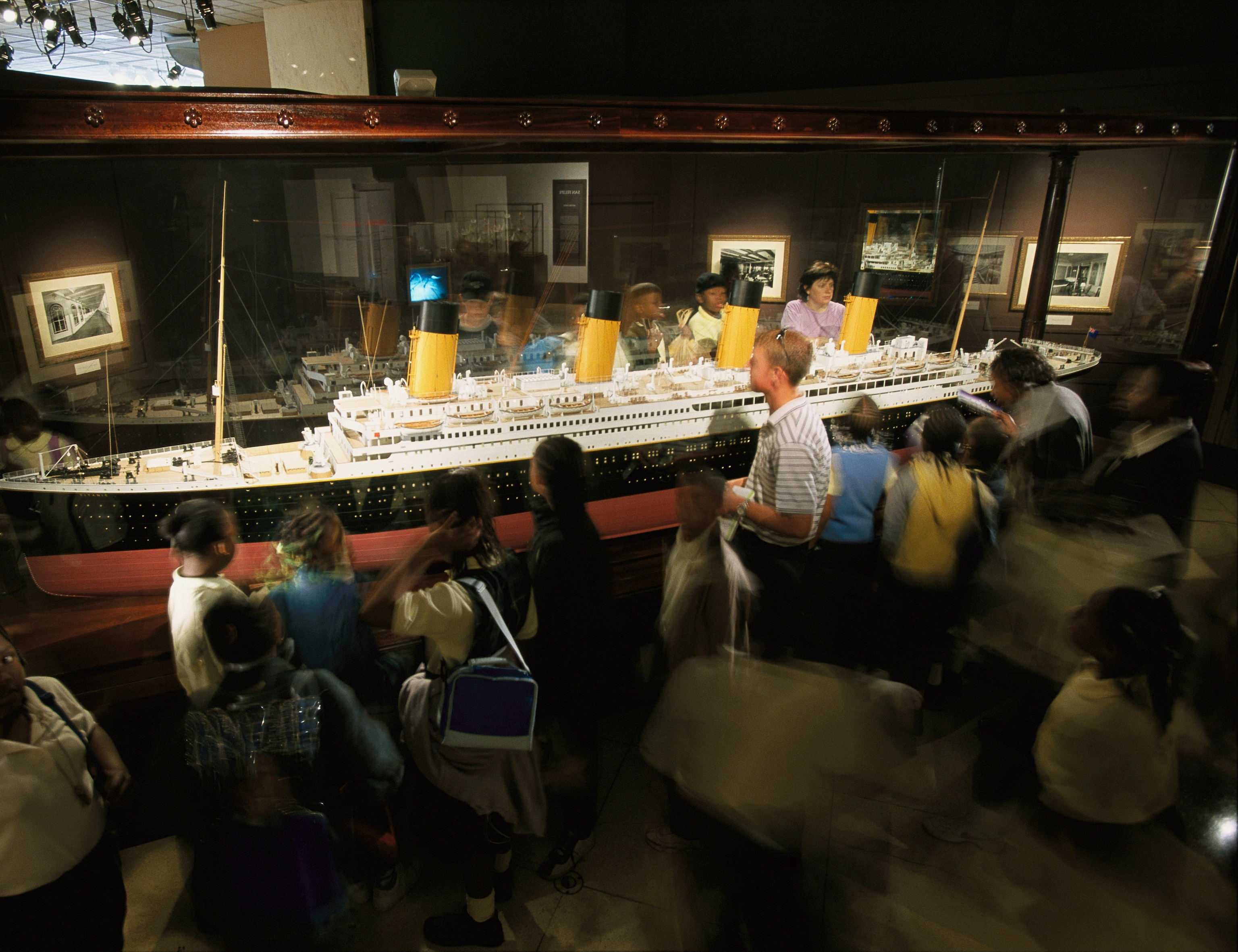 A group of visitors examining a scale model of the Titanic.