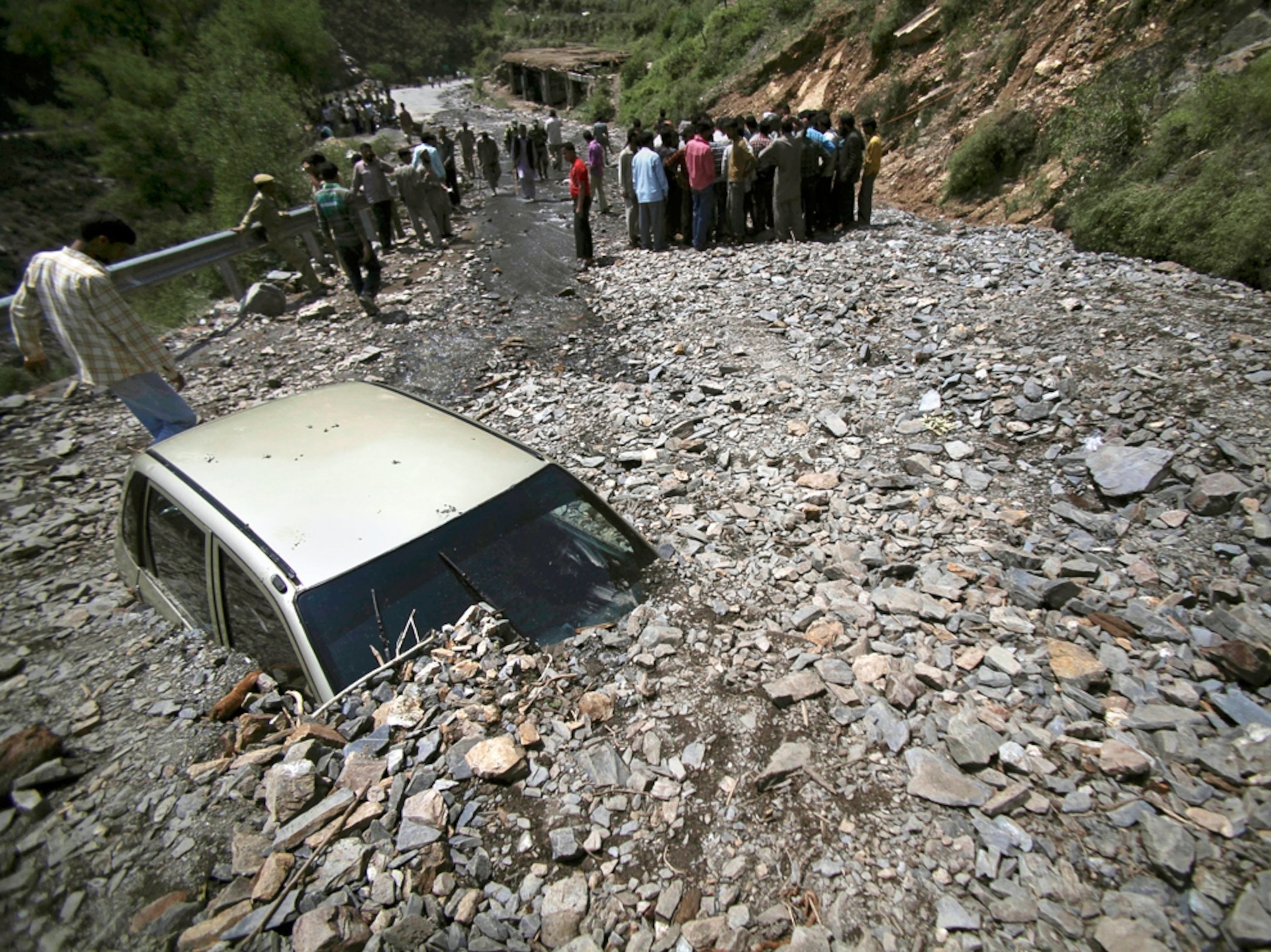 a car buried under landslide rubble in India