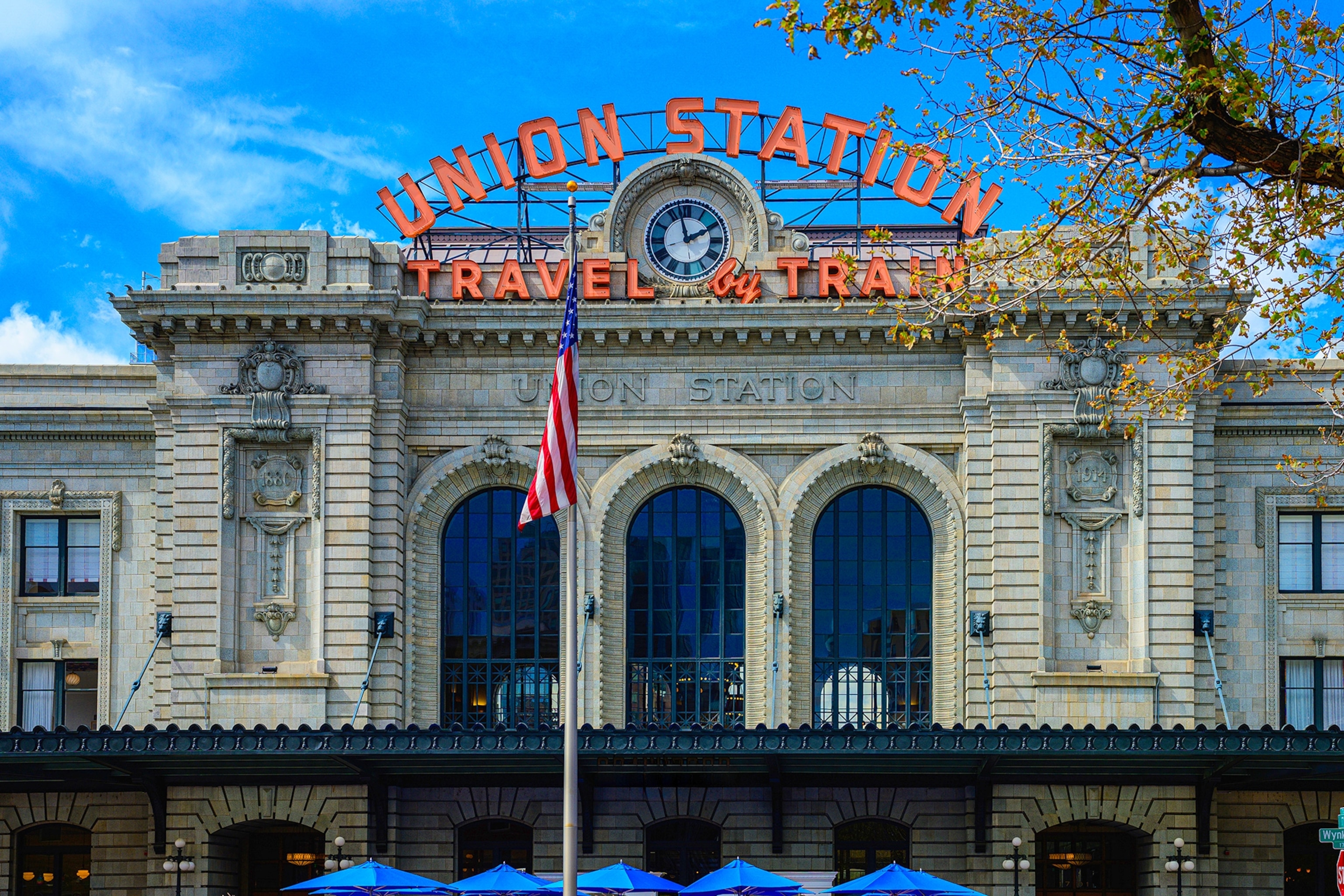 The exterior of a train station with light lettering in an arch above the entrance.