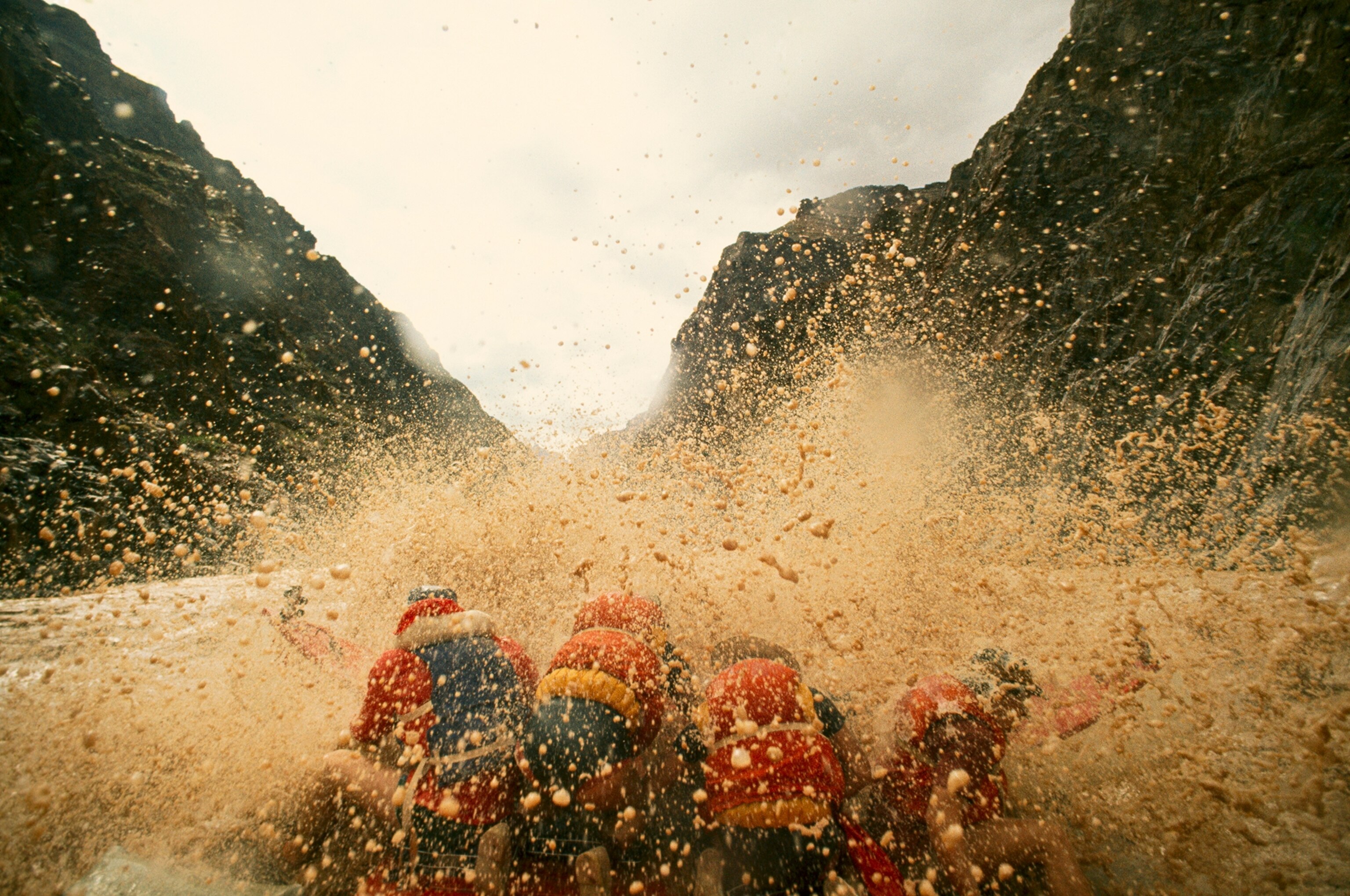 Muddy rapids and spray engulf rafters.
