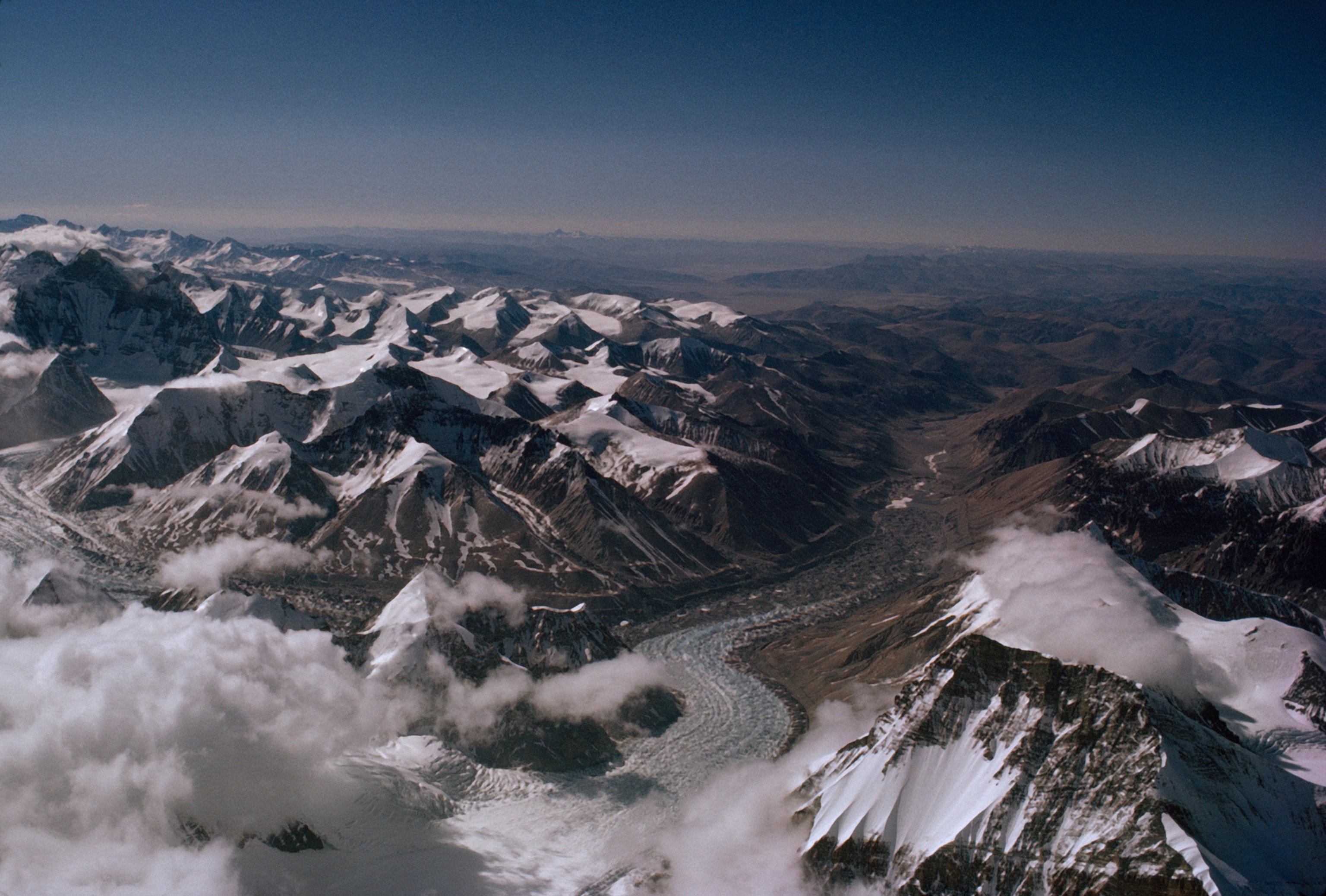 Tibet’s rolling hills stretch to the horizon in a view from Everest’s summit. West Rongbuk Glacier at left flows into the main Ronbuk. Hundred-foot ice pinnacles, formed by differences in melting, break the surface of the frozen river.