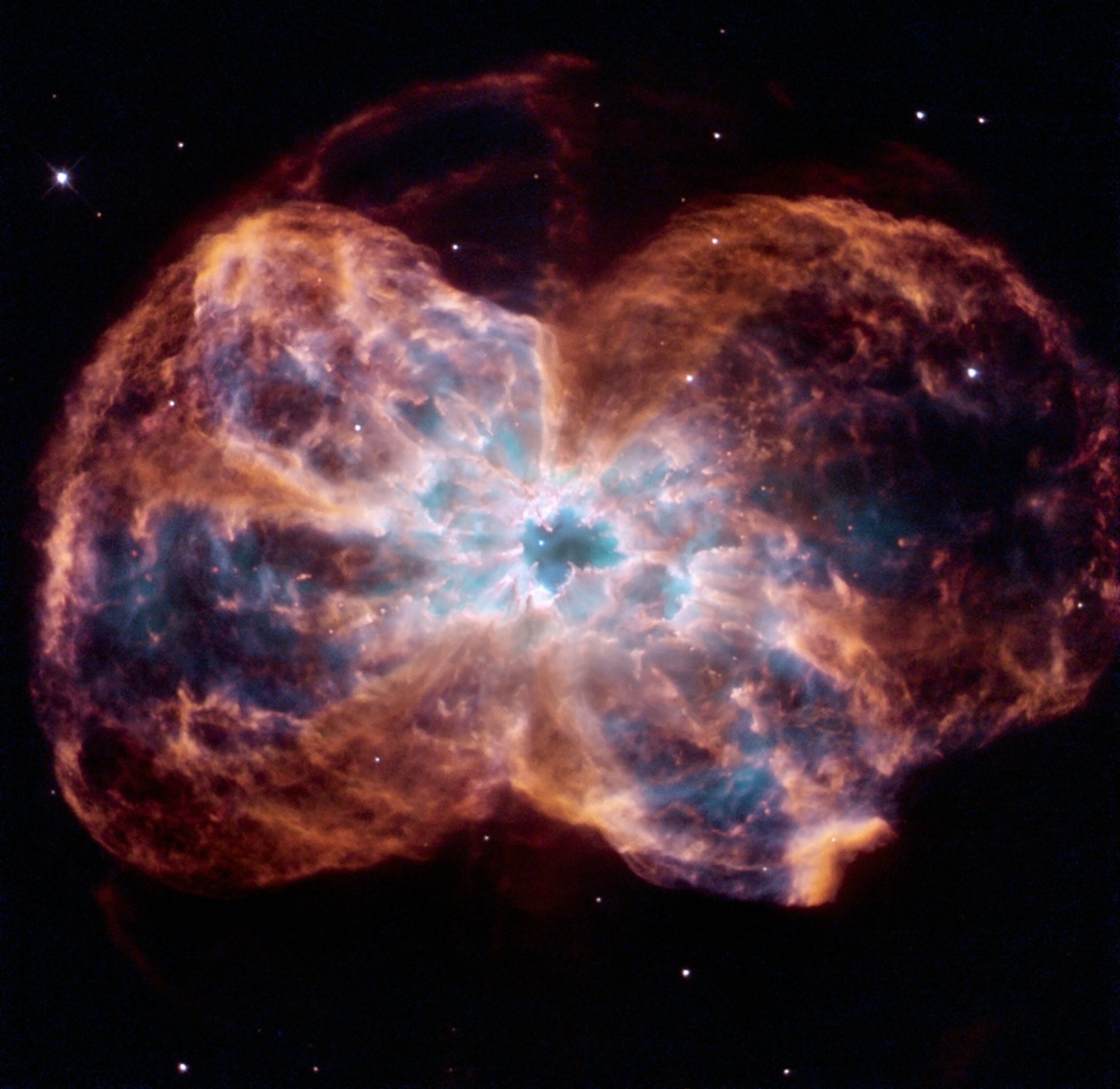 A colorful, bow tie-shaped planetary nebula surrounds a dying white dwarf.