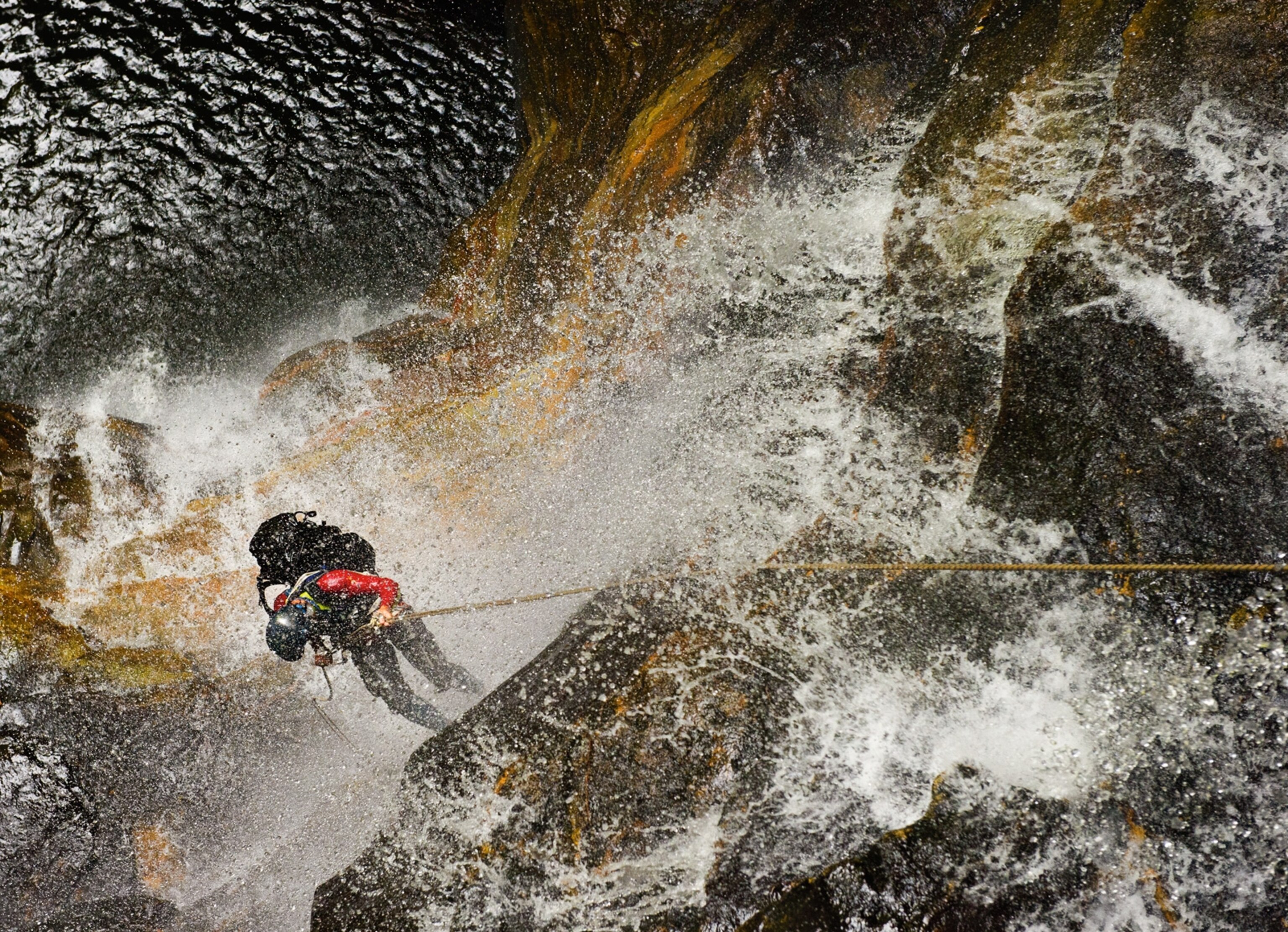 a canyoneer enduring the deluge of a waterfall in Empress Canyon