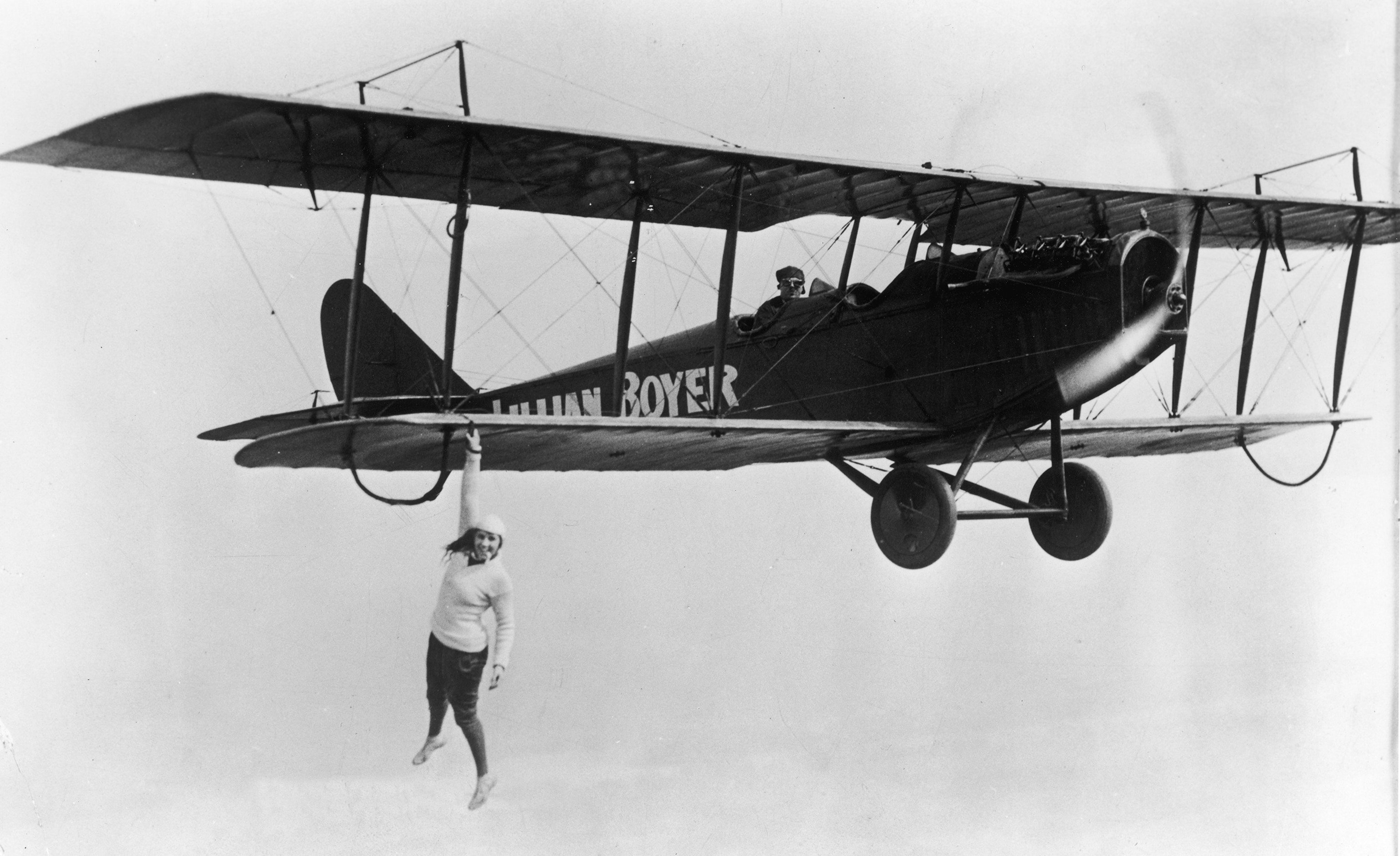 Lillian Boyer hanging off the wing of a flying airplane, circa 1923.