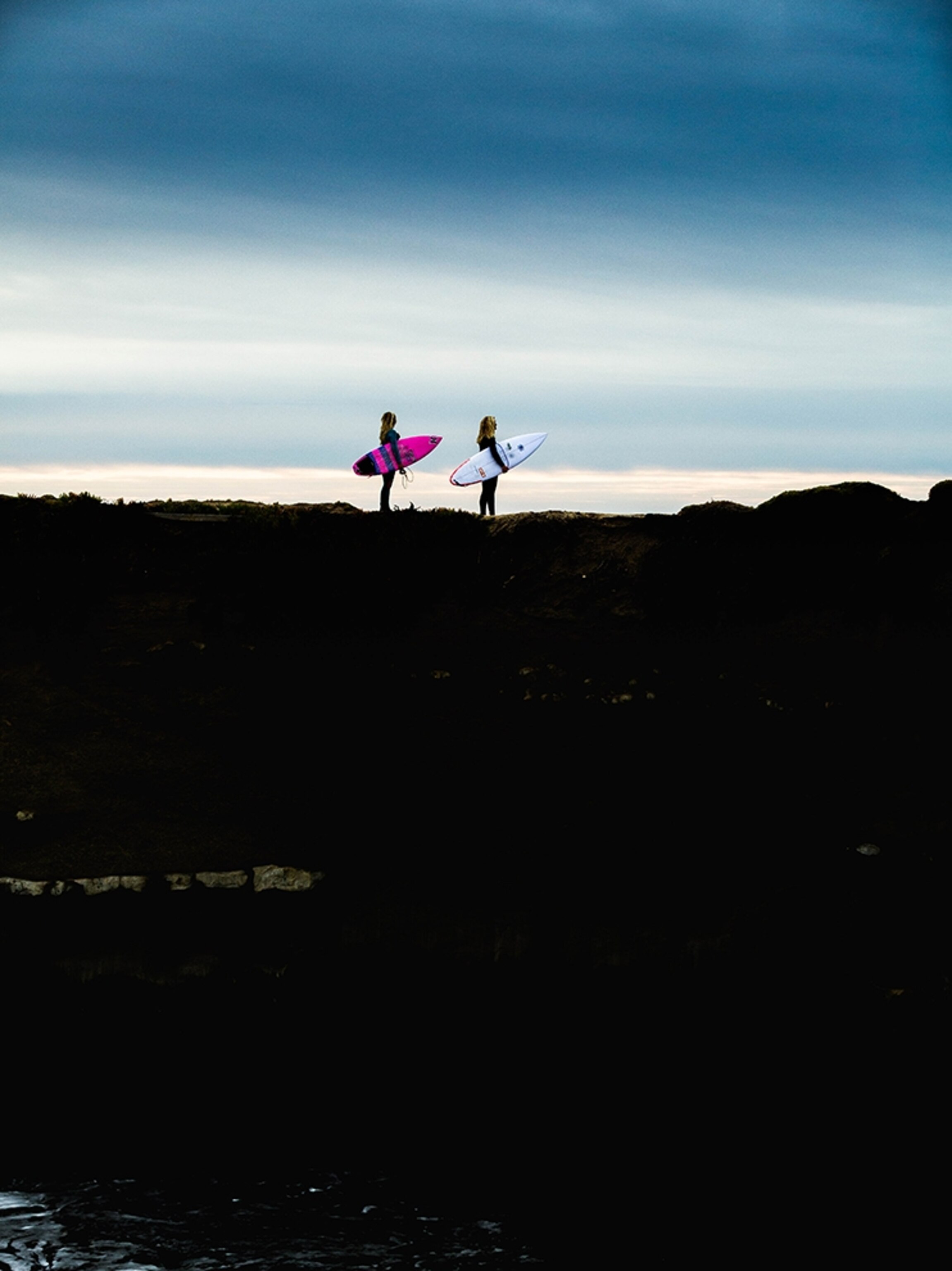 two surfers looking out at the ocean