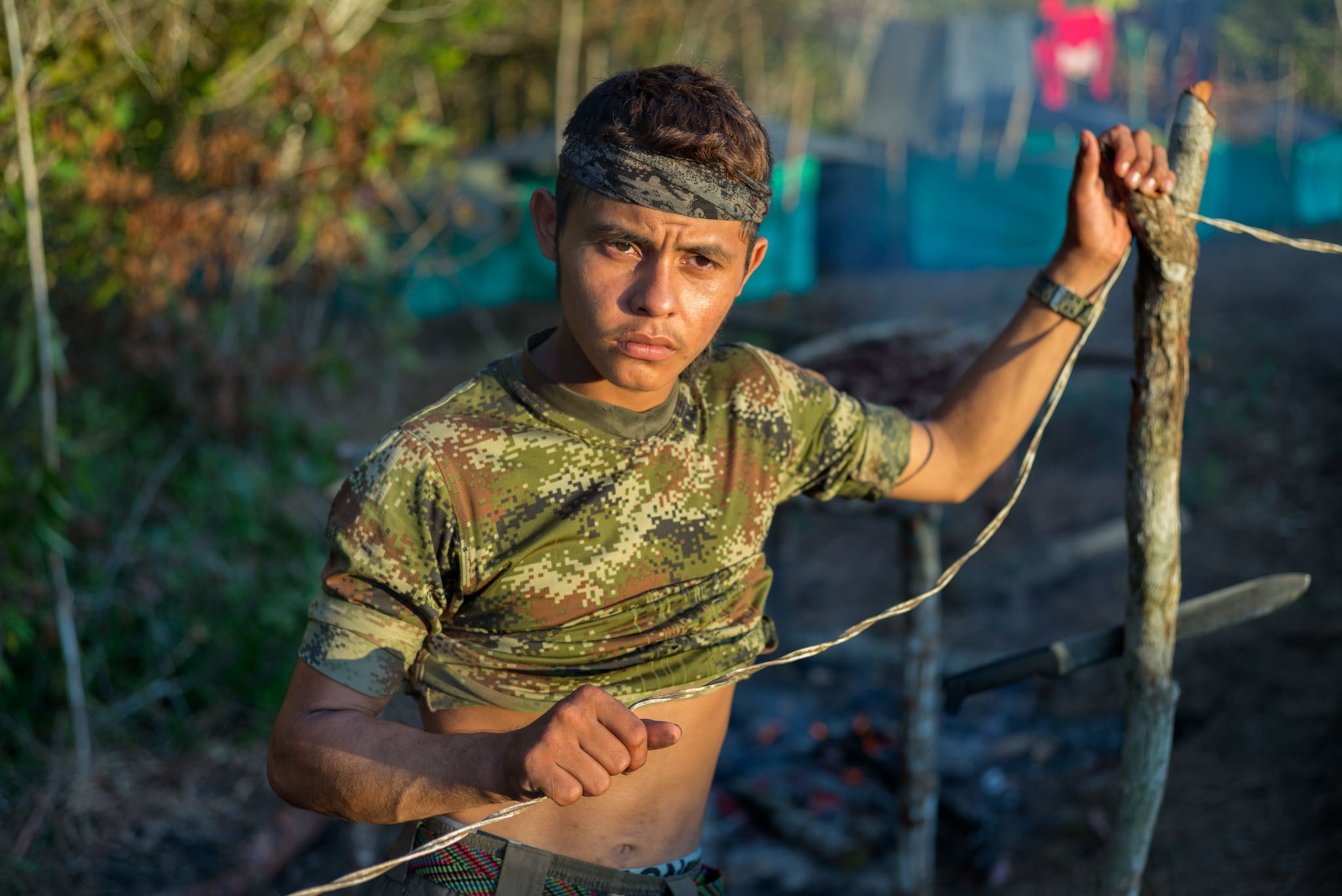 a young man in a camouflage shirt staring off in sunset light