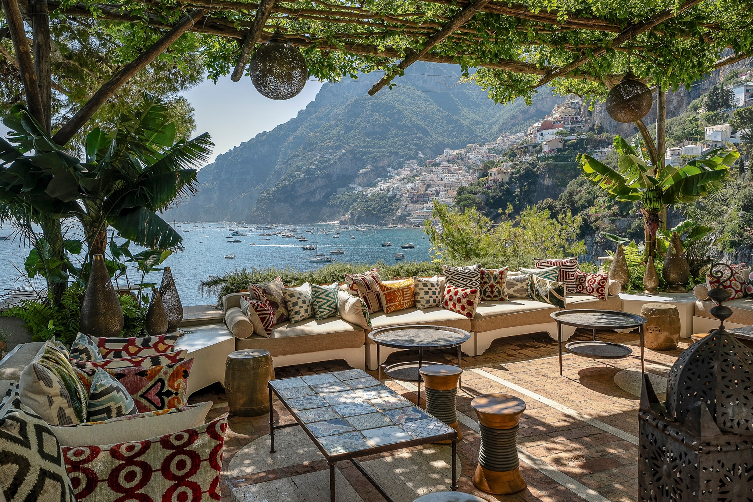 A terrace lined with cushion-strewn sofas overlooking the coast and cliffs.