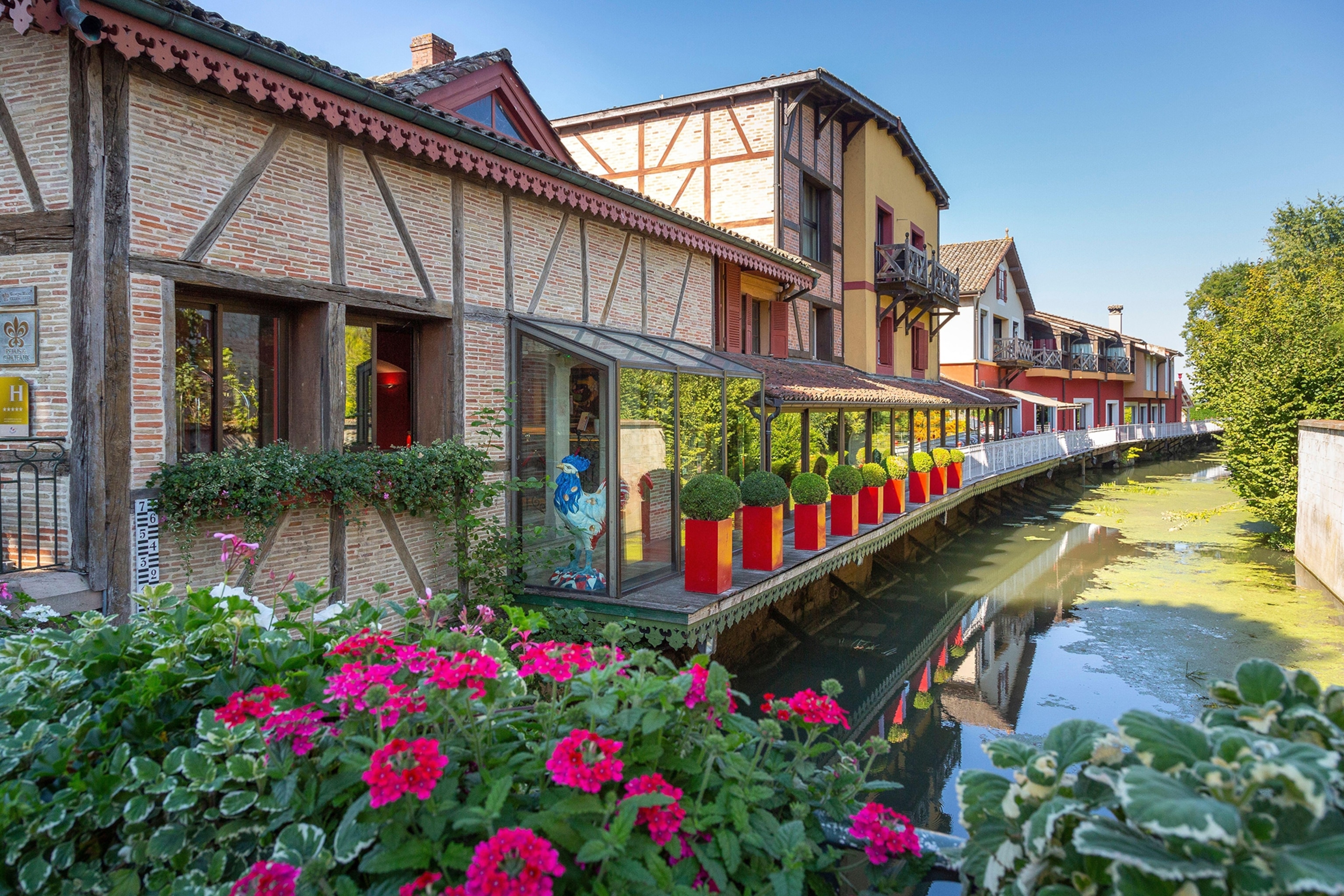 The exterior, river-front dining terrace of a half-timbered restaurant in eastern France.