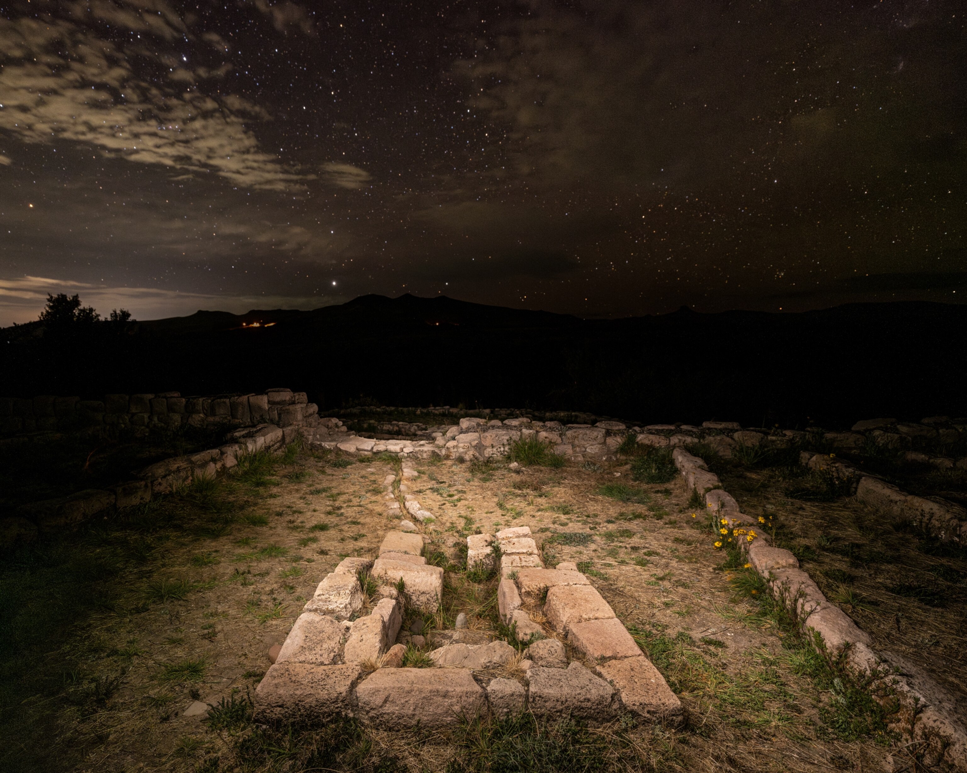 Night view of the stone-lined water feature and yellow flowers growing between stones.