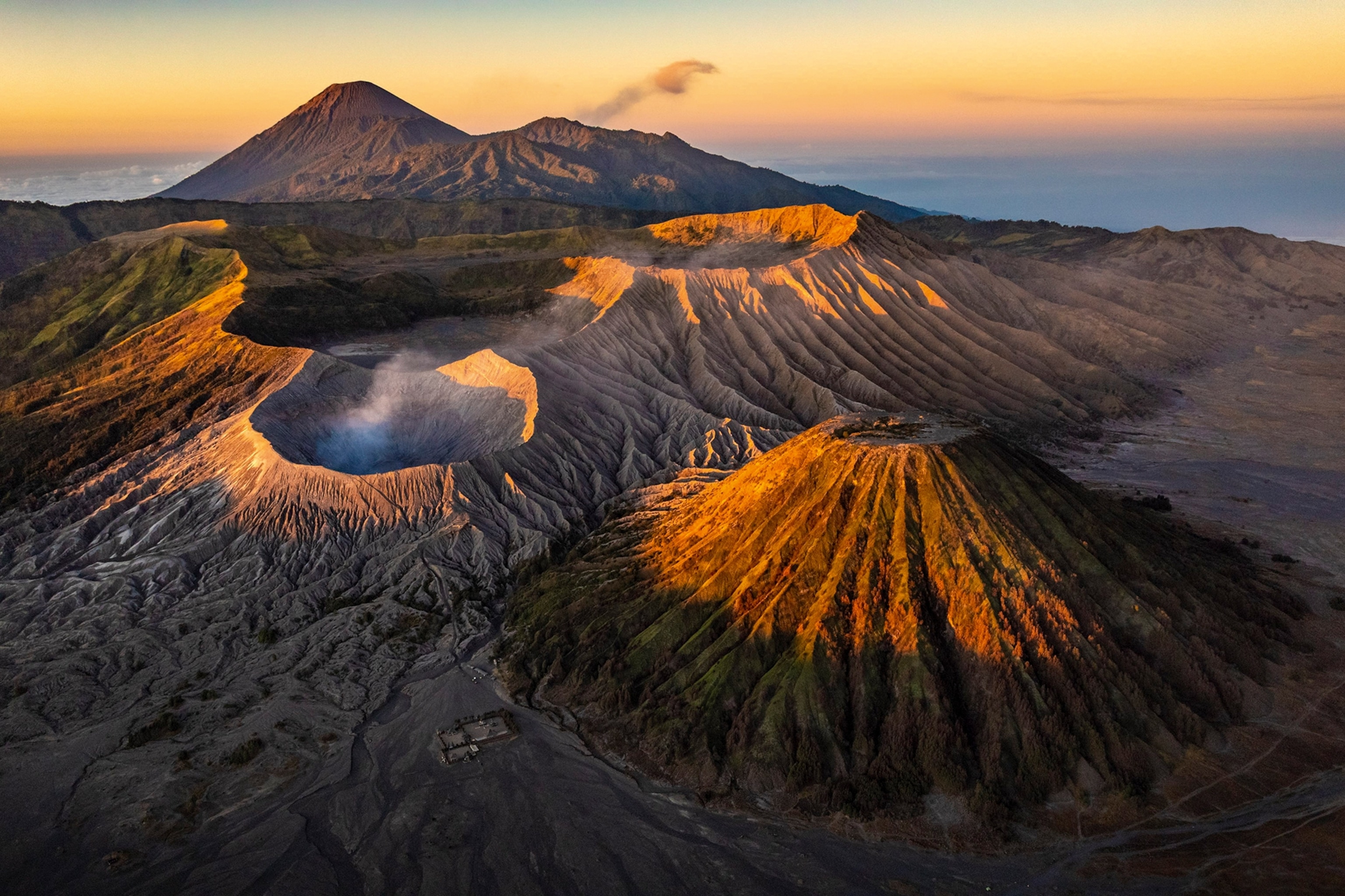 An aerial shot of a volcano landscape with multiple peaks during sunset.