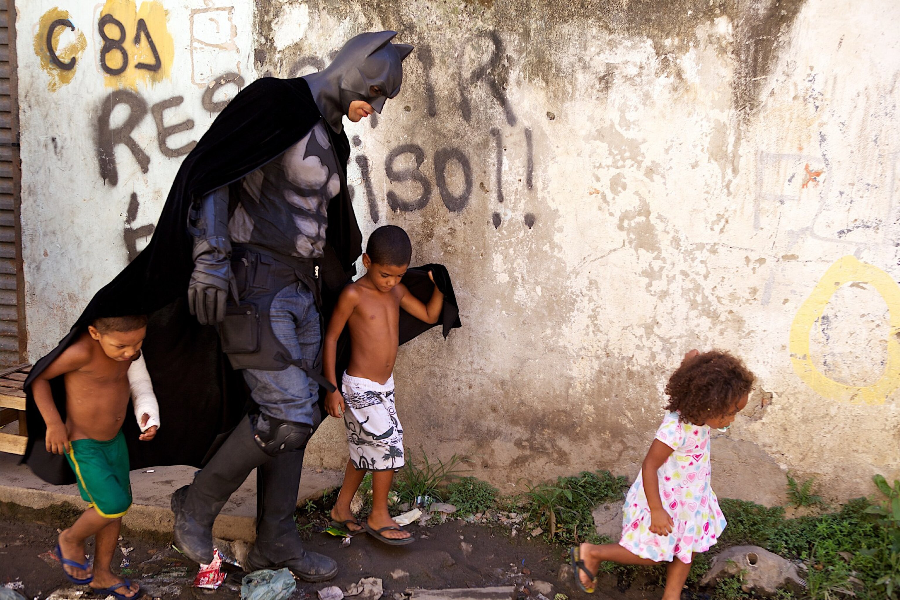 a man dressed as Batman with children in Rio