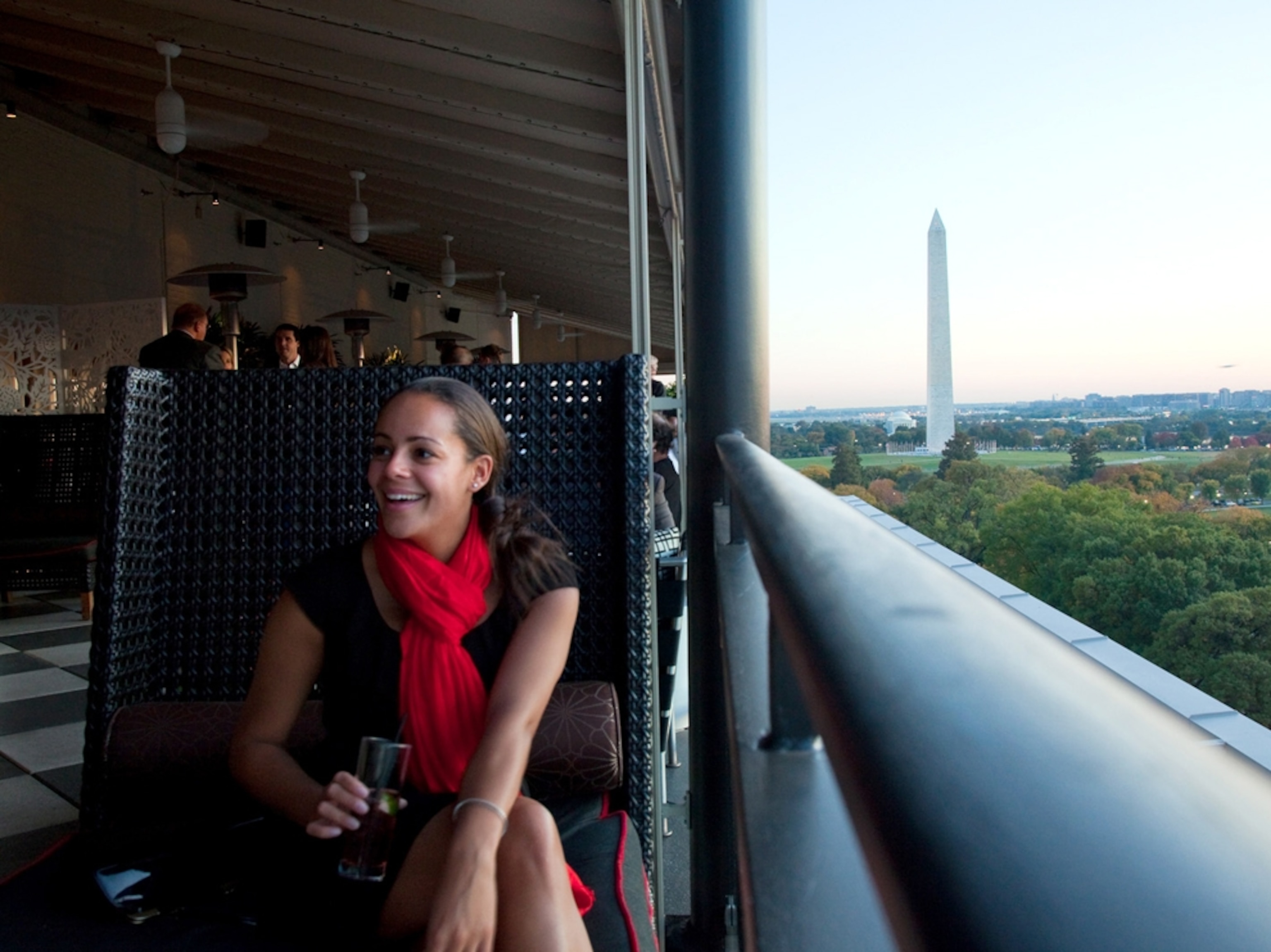 A woman enjoys a drink at hotel overlooking Washington Monument, Washington D.C.