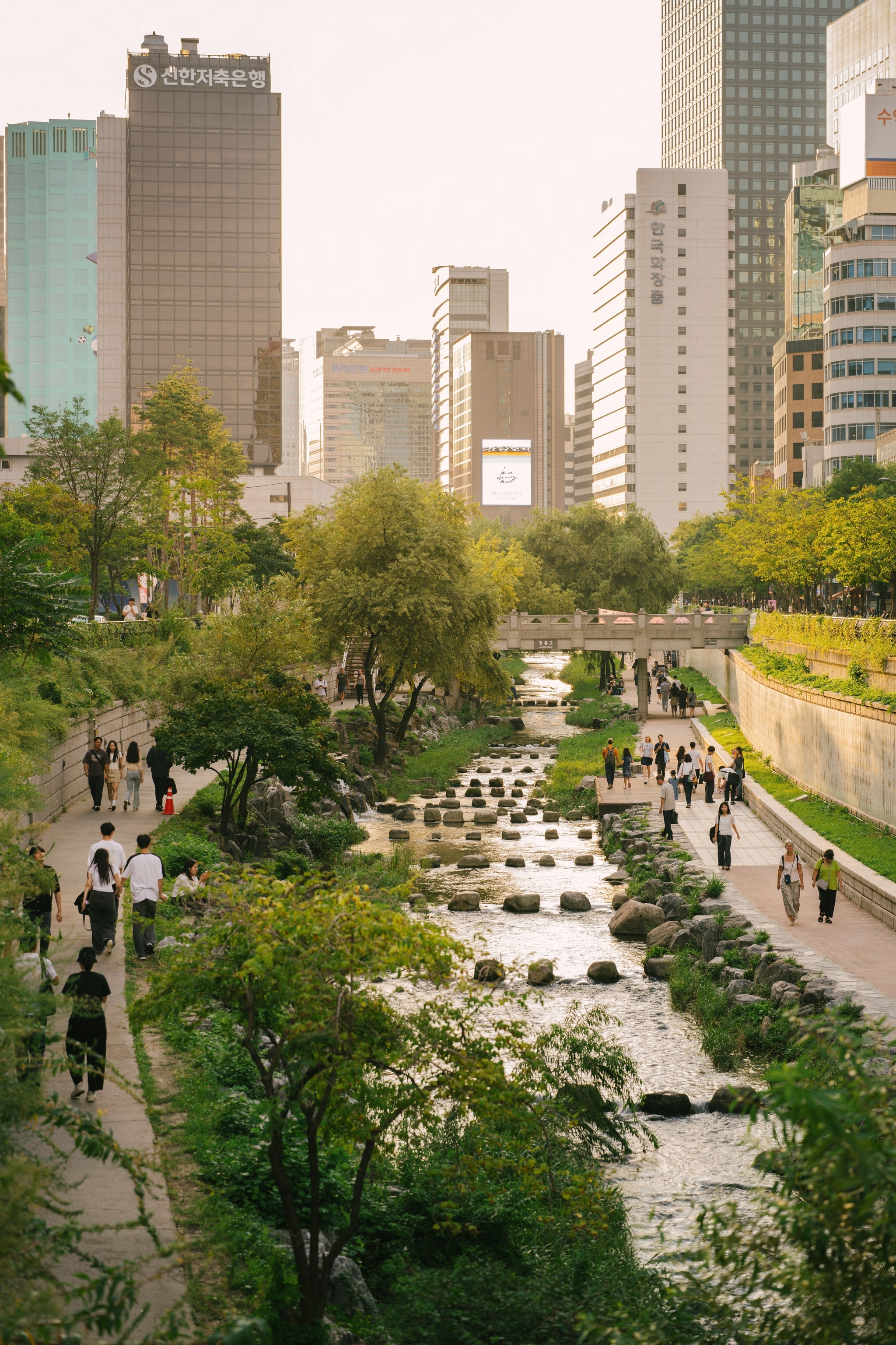 Stream with paths next to it, with city-goers walking by