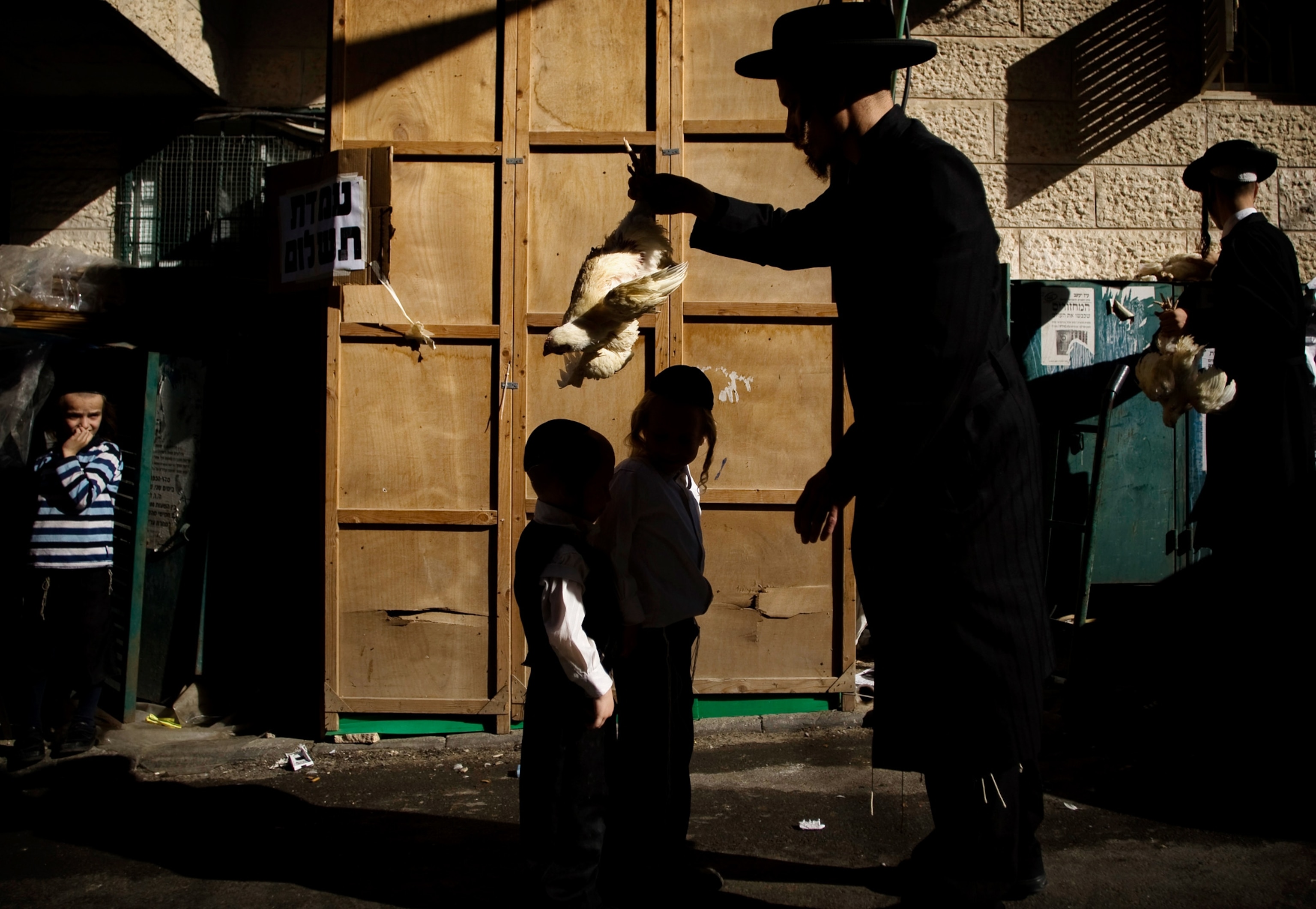 Pictures We Love - Picture of an ultra-Orthodox Jew swinging a chicken over the heads of two children in a ritual act of atonement