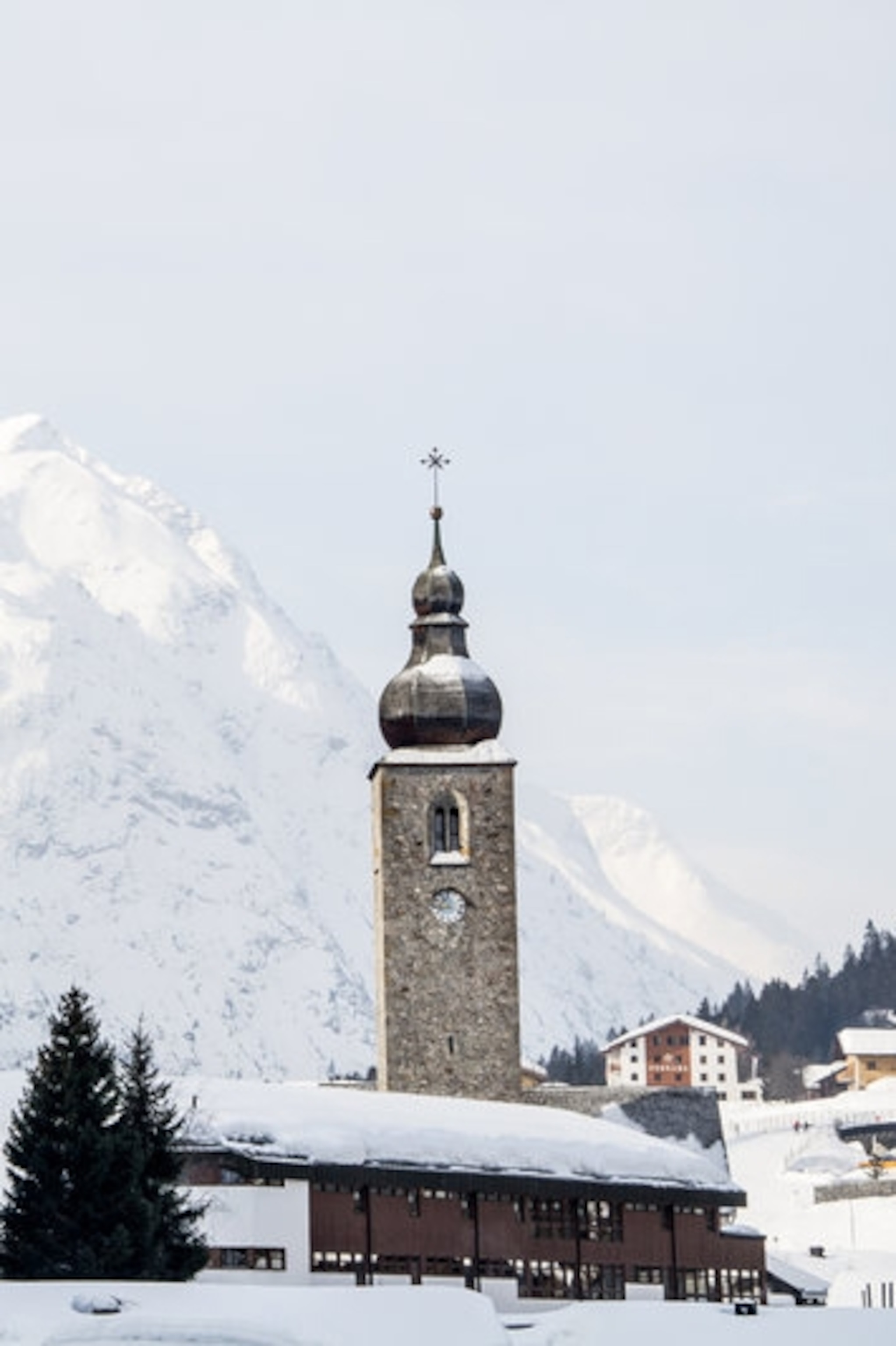 A mountain village in a snowy valley with a domed church.