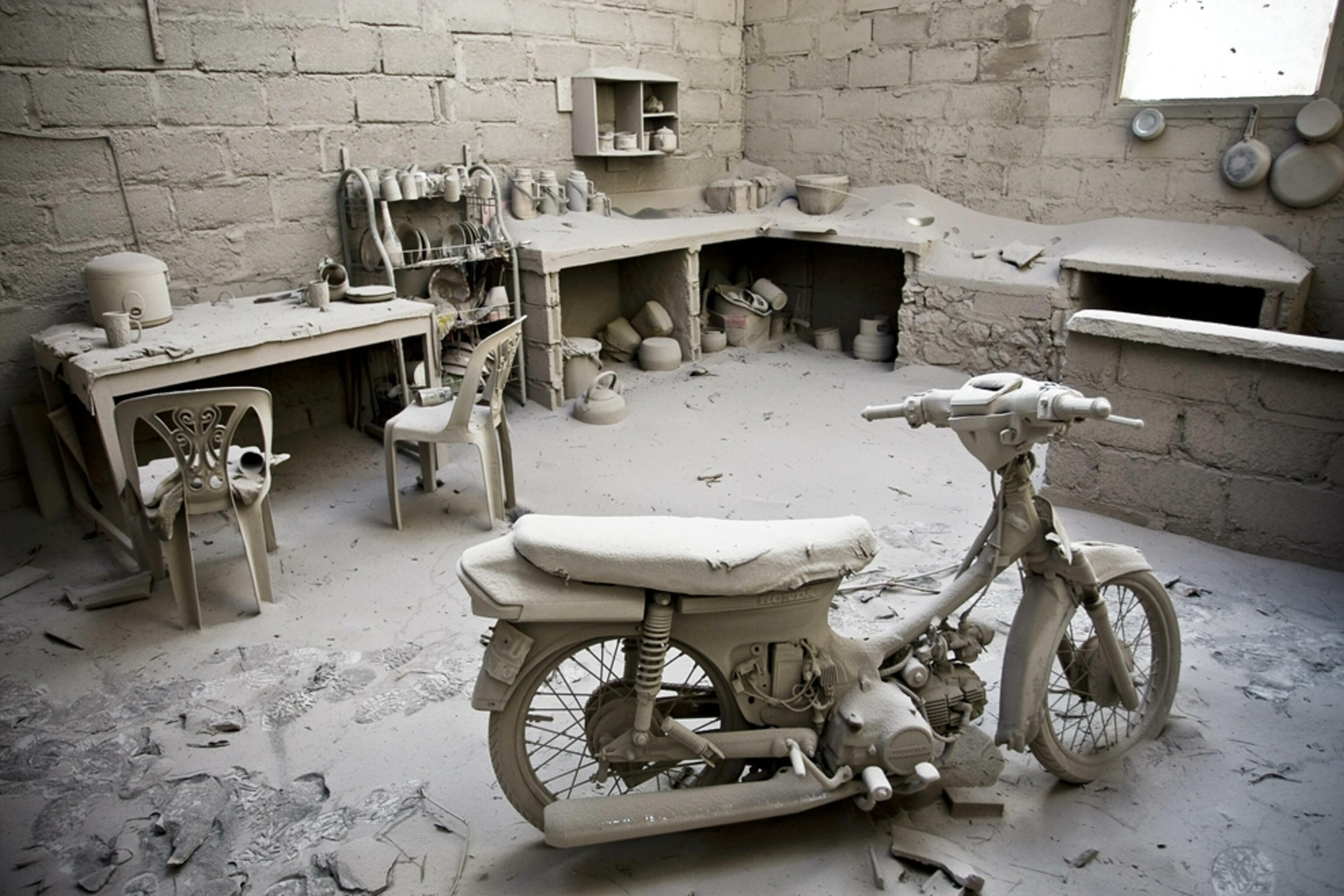 A motorcycle covered in ash from the Indonesian Mount Merapi volcano eruption is seen inside a home.
