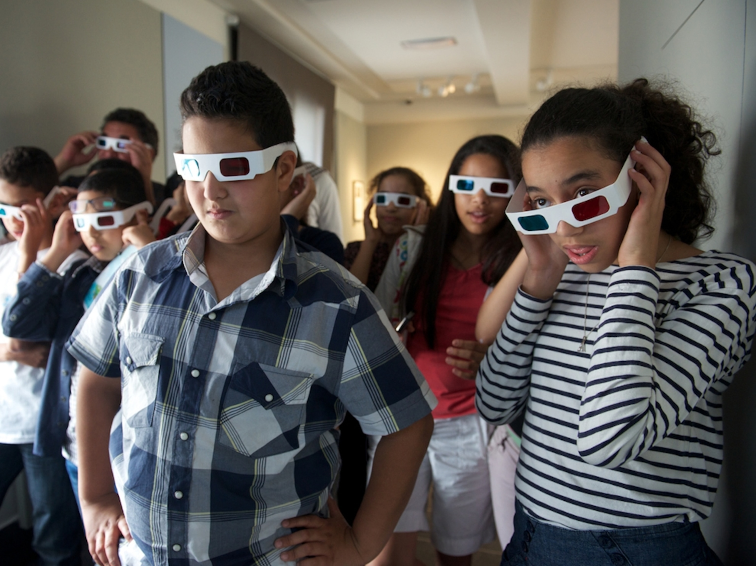 schoolchildren viewing the photography of Gabriel Veyre with 3-D glasses
