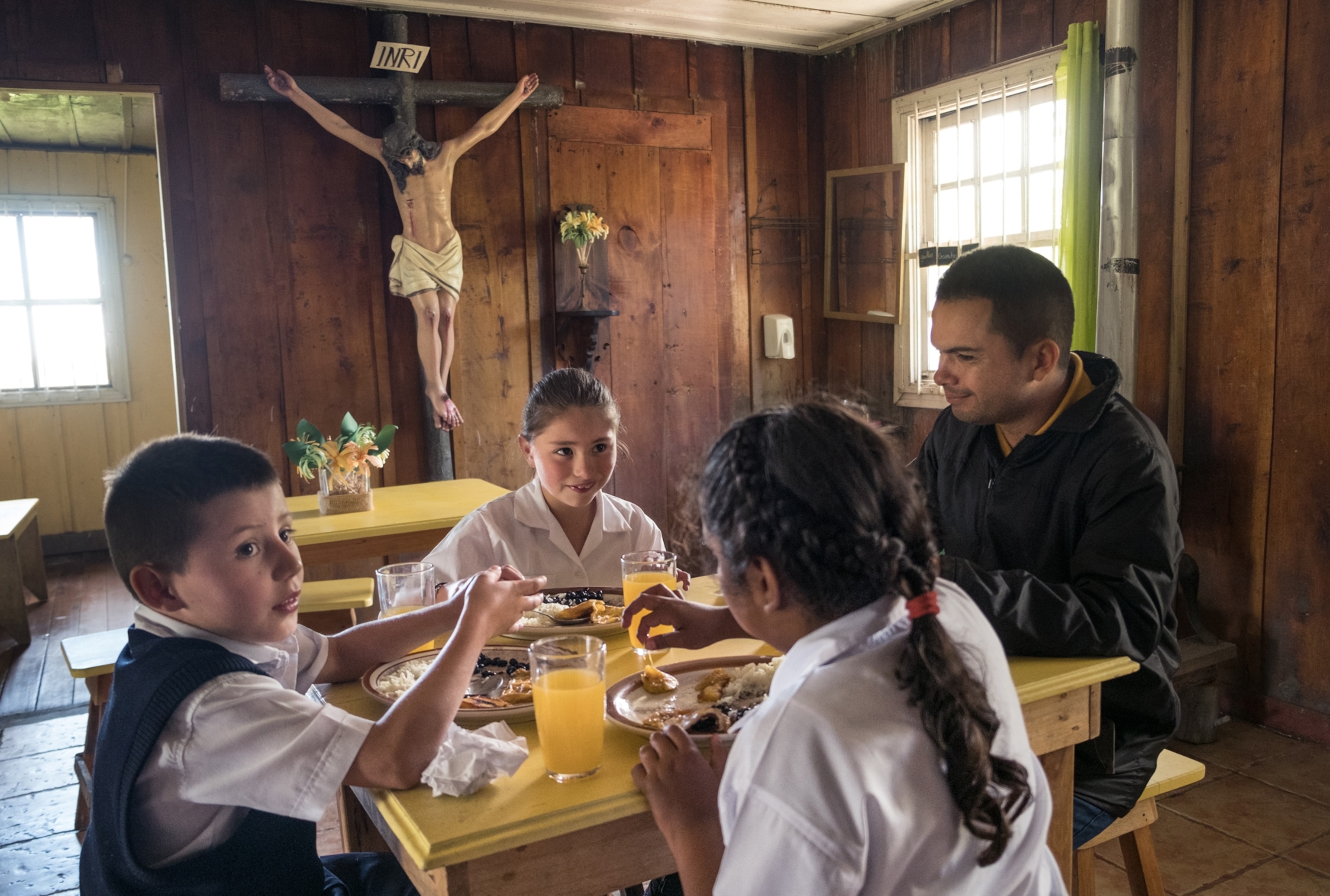 three students in La Central, Cartago, Costa Rica, eating lunch with their teacher.