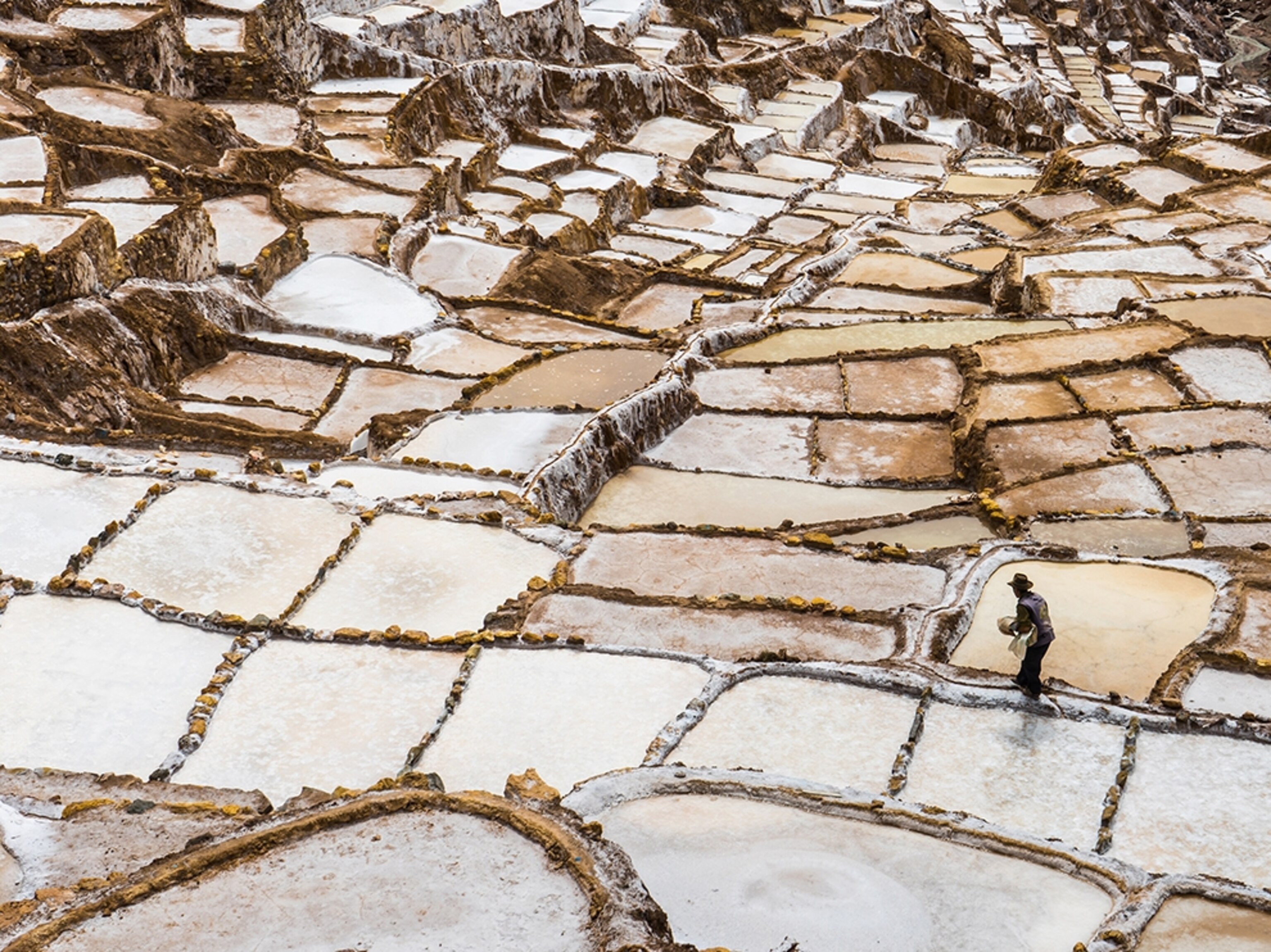 man working in the salt ponds of Salinas de Maras, Peru