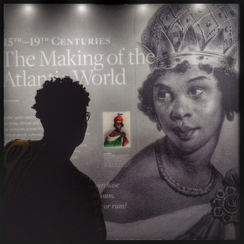 A woman leans in to take a closer look at an exhibit about African contributions to "The Making of the Atlantic World".
