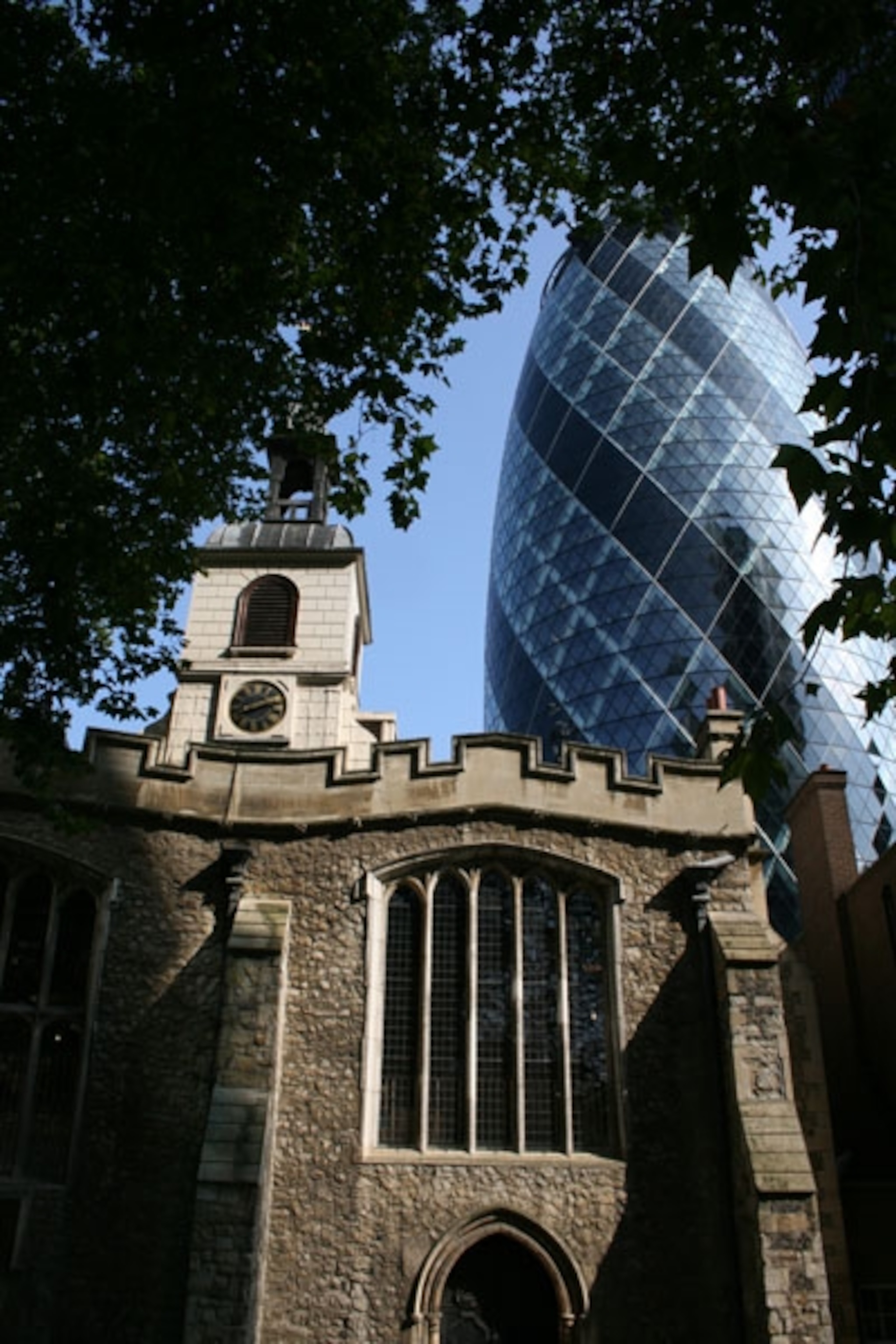 An older building in front of the modern one known as the Gherkin, in London