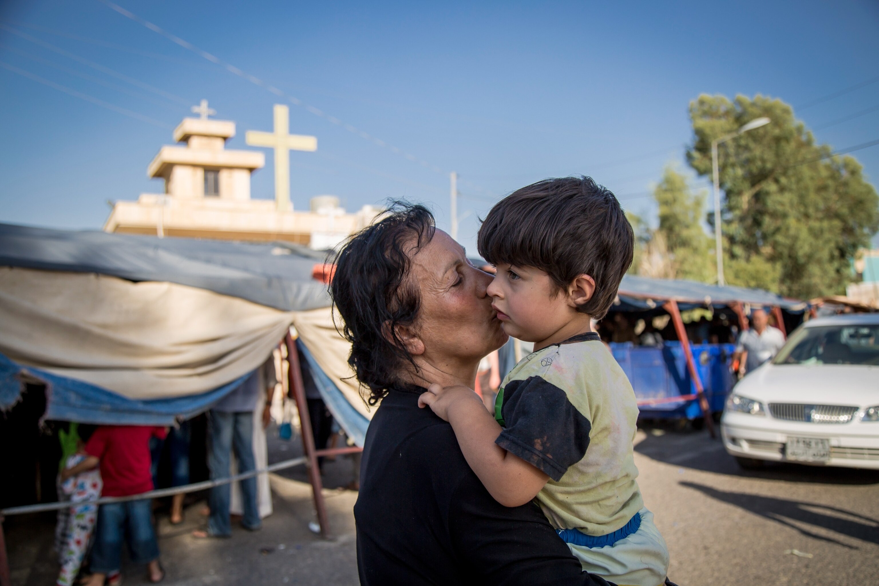 woman kissing a small boy in front of the Mar Tshmony church.