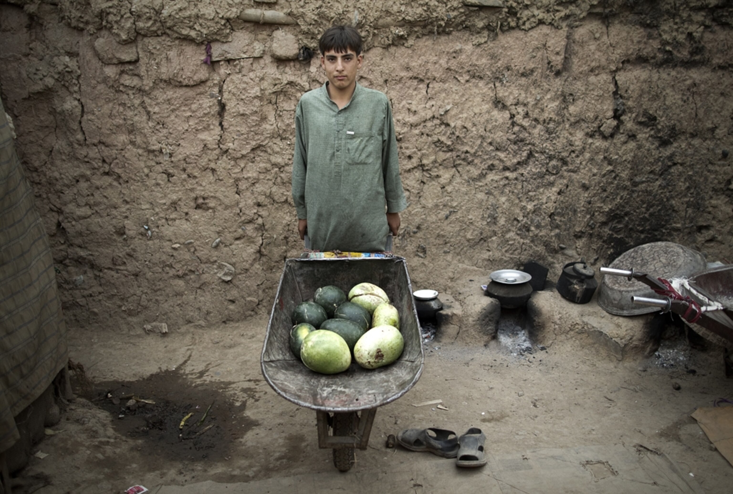 Photos: A young man stands with a wheelbarrow full of watermelons