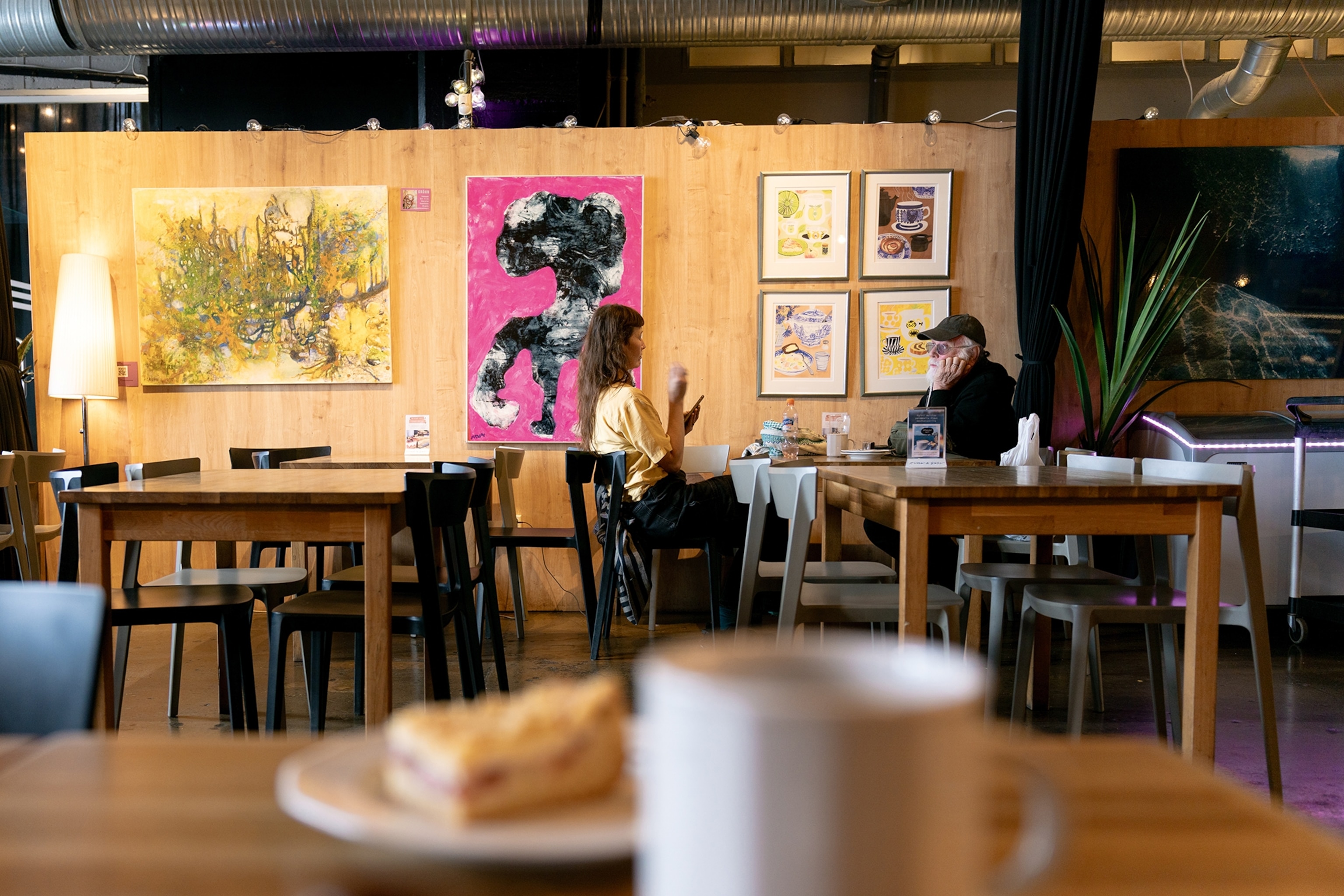 A voyeurist shot of a cafe with simple plywood walls and framed art.