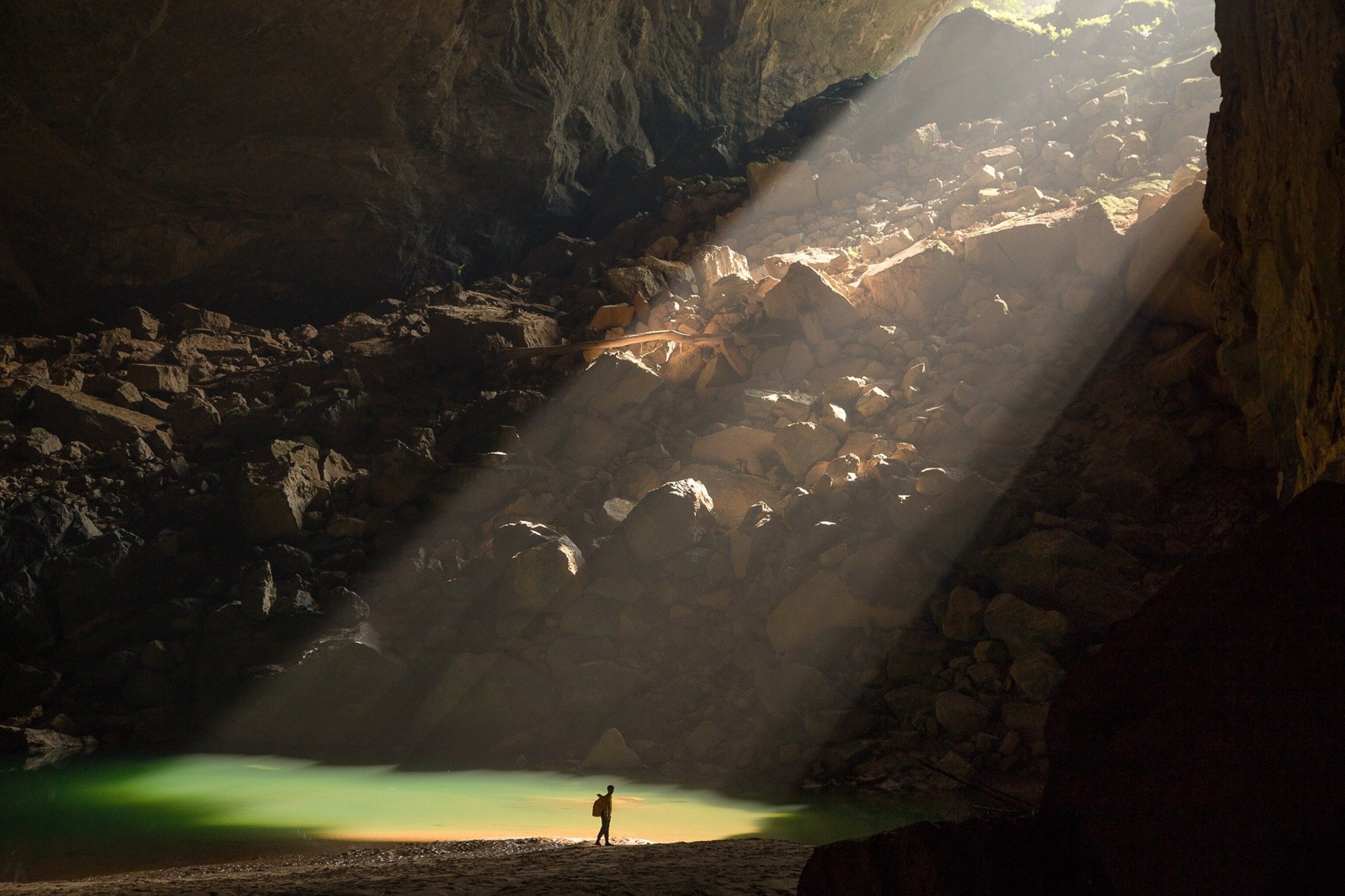 the sun shining through the entrance of Hang En cave in Vietnam
