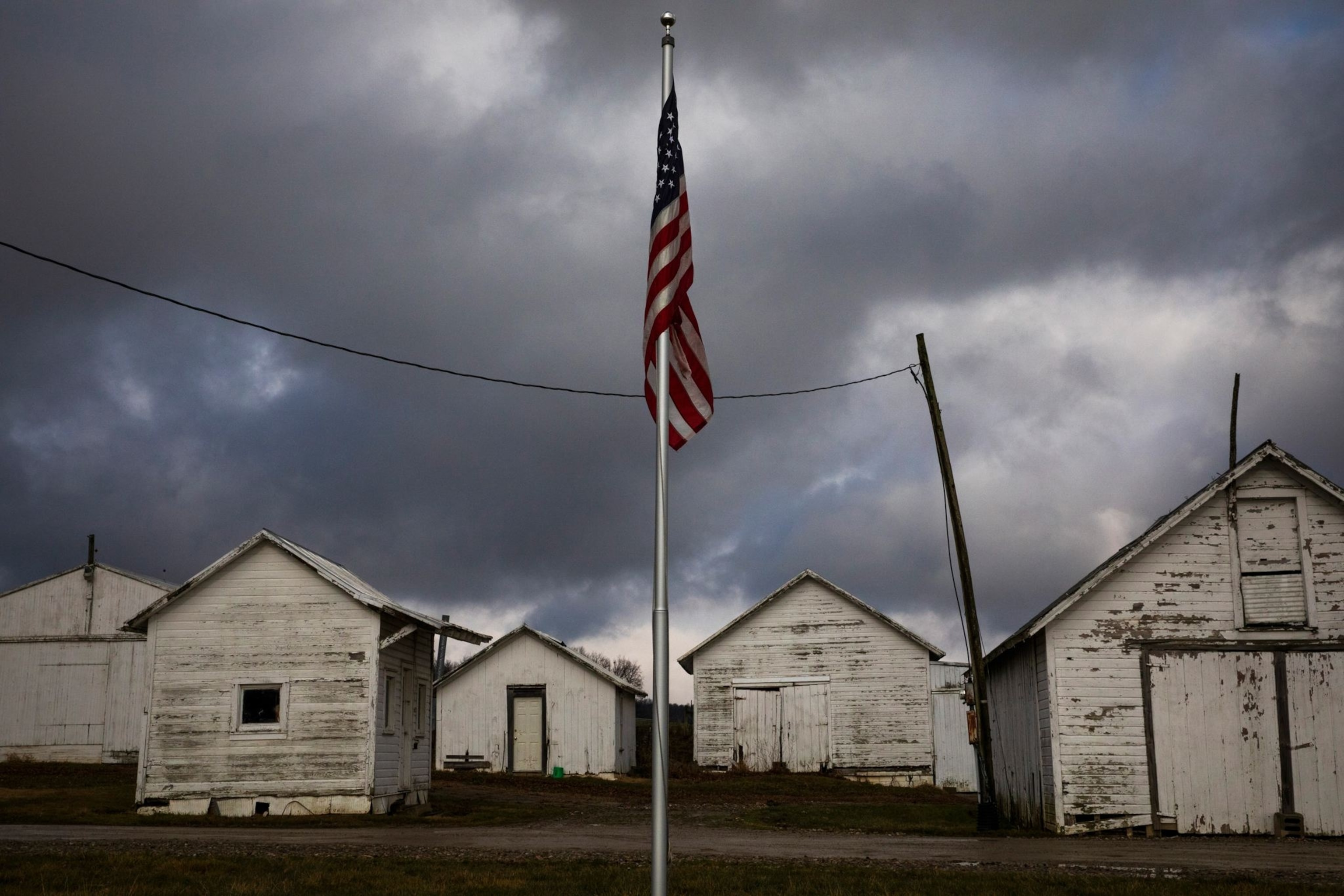 A U.S. flag stands in front of farm buildings