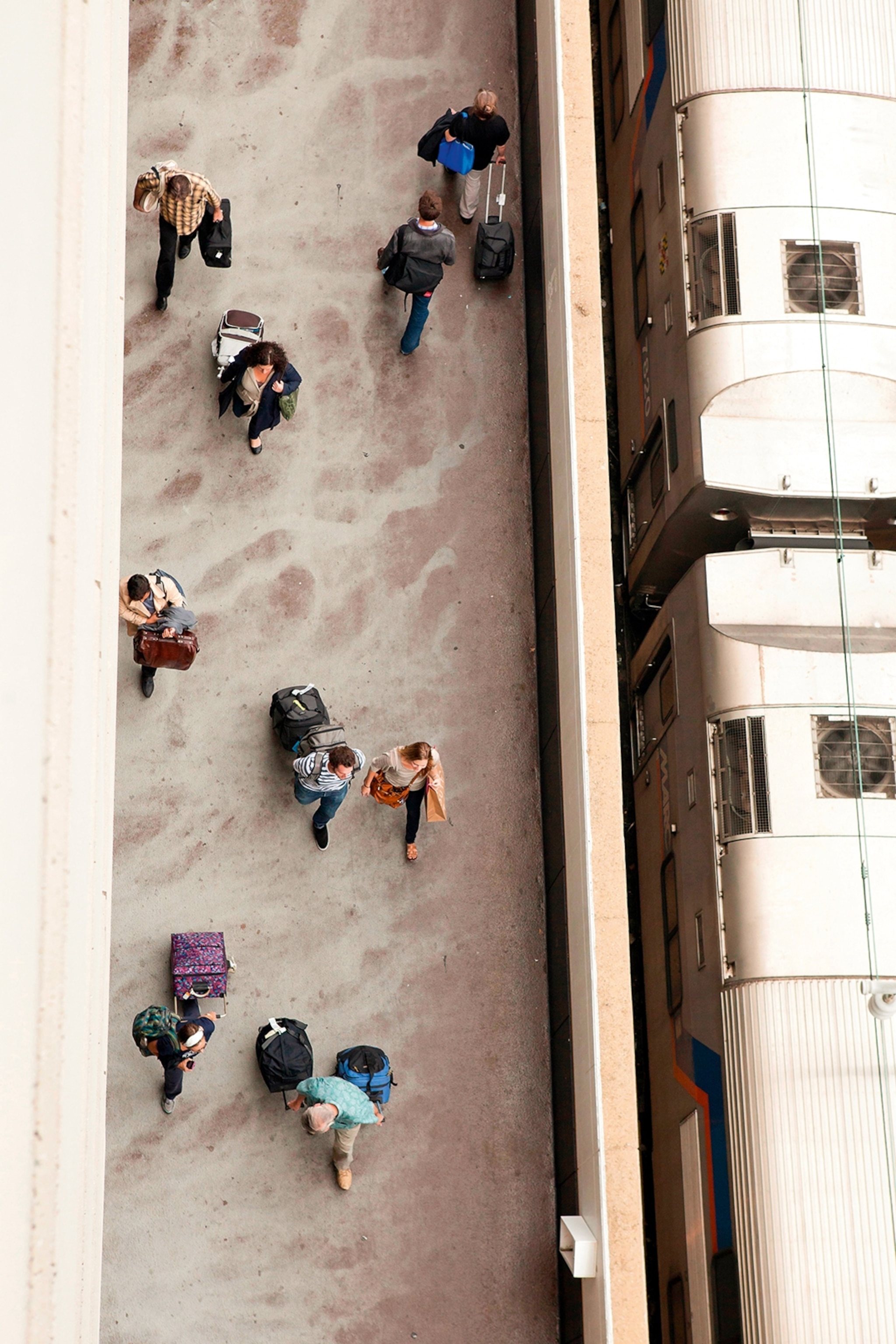 Commuters at a train station shot from above with a train halted on the side.