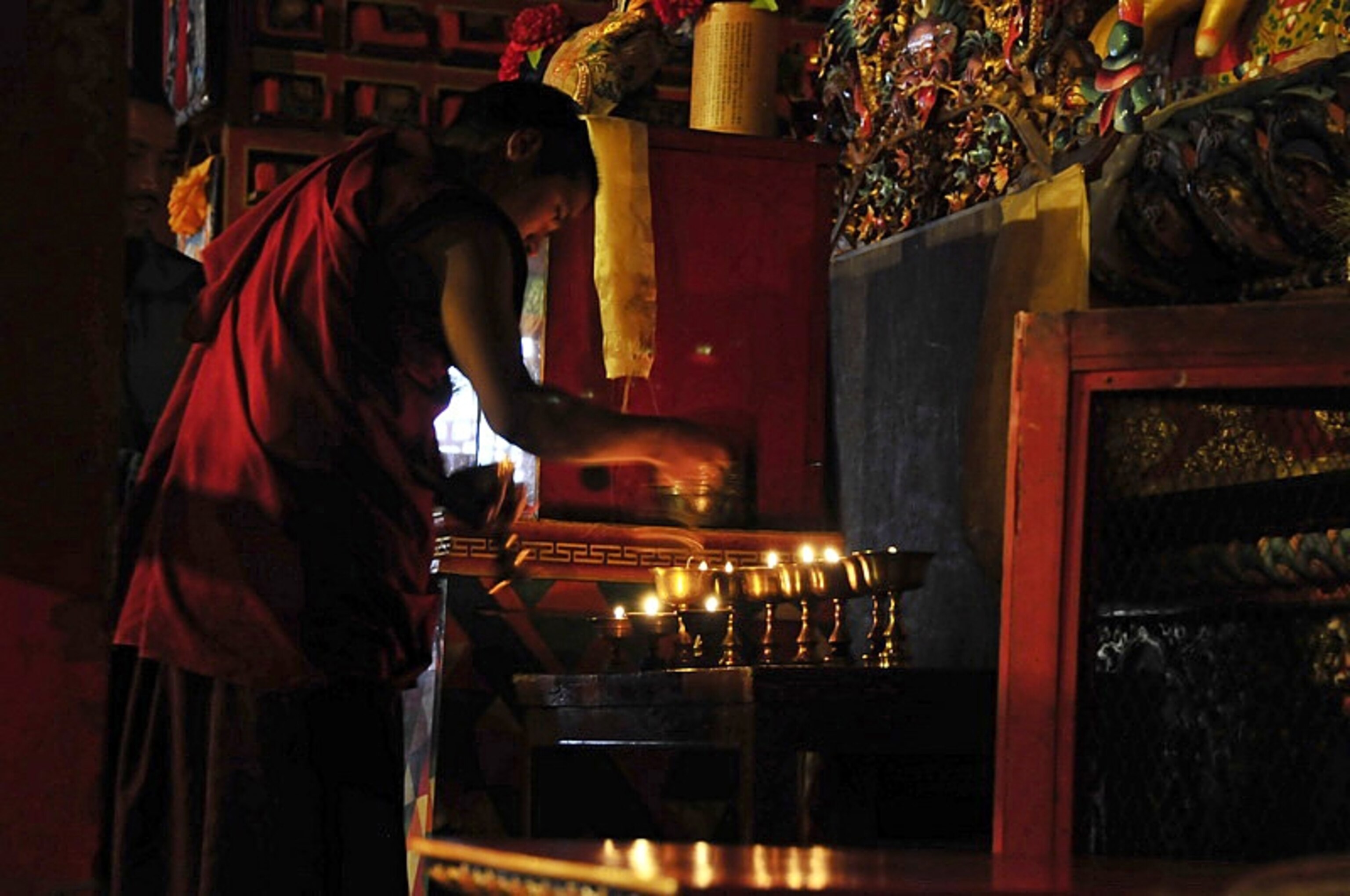 A monk lights butter lamps at Thyangboche Monastery