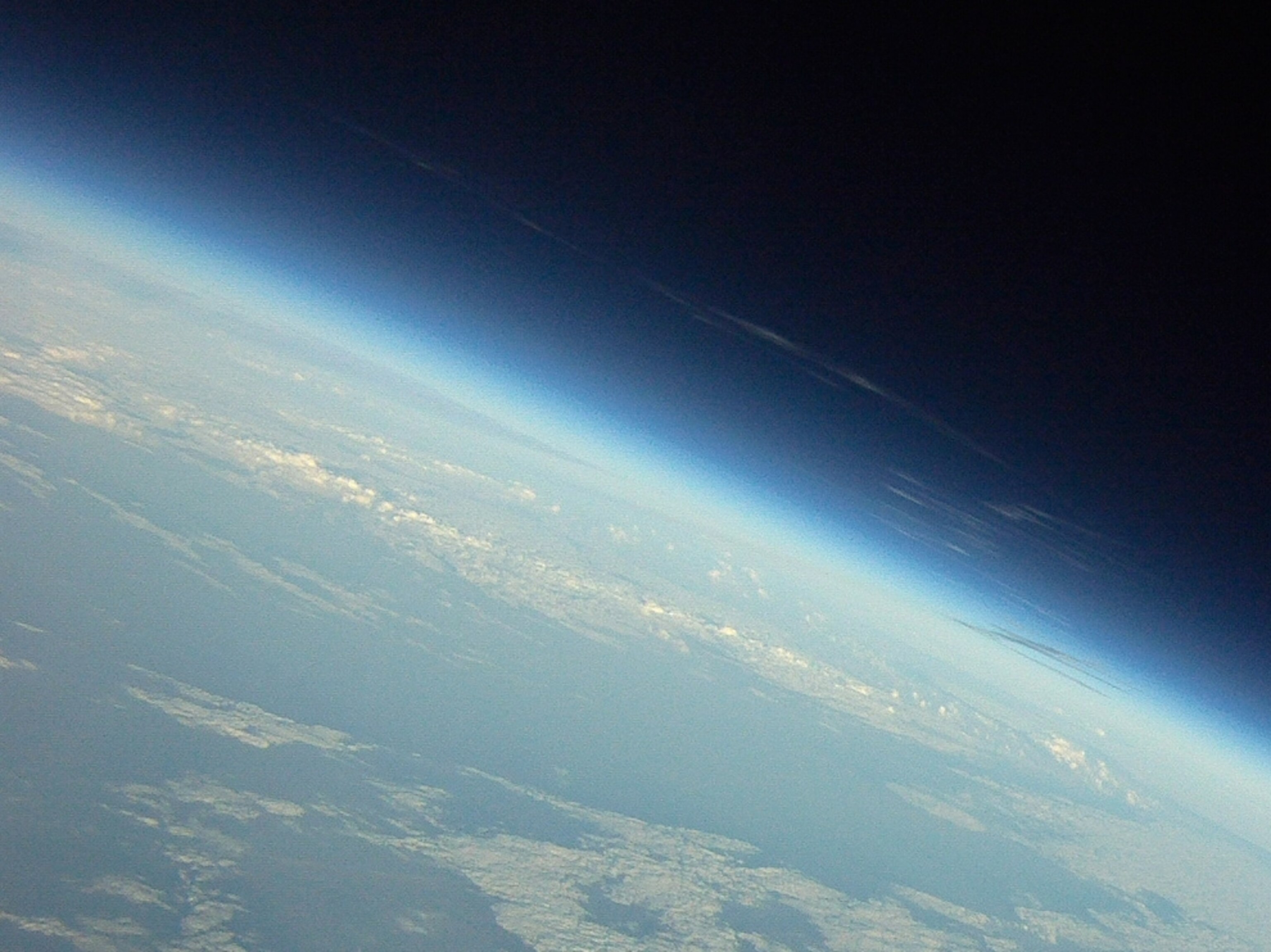 Discovery's exhaust trail fanned out by the jet stream high above Earth