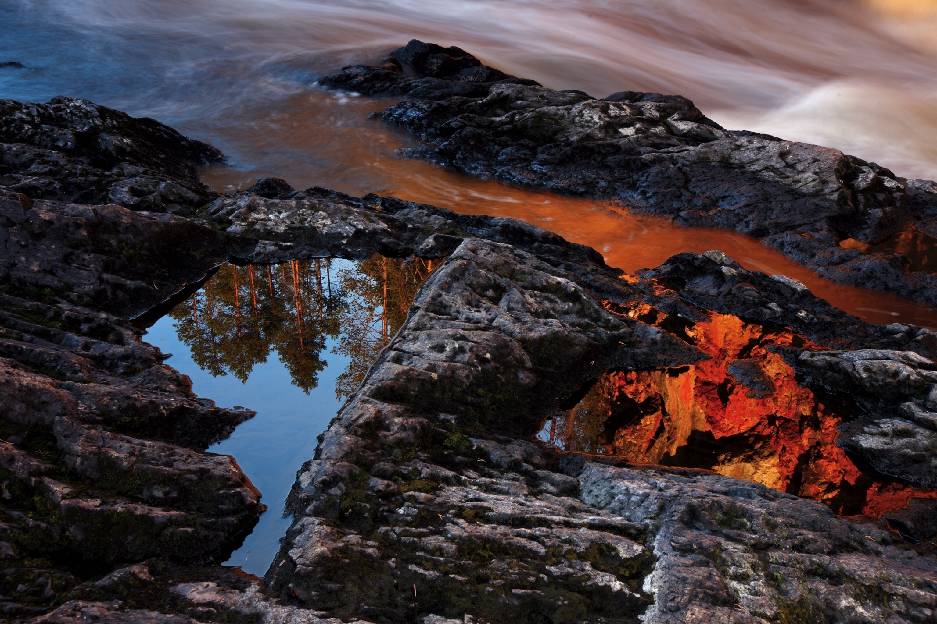a still pool mirroring its surroundings at sunrise in Oulanka National Park