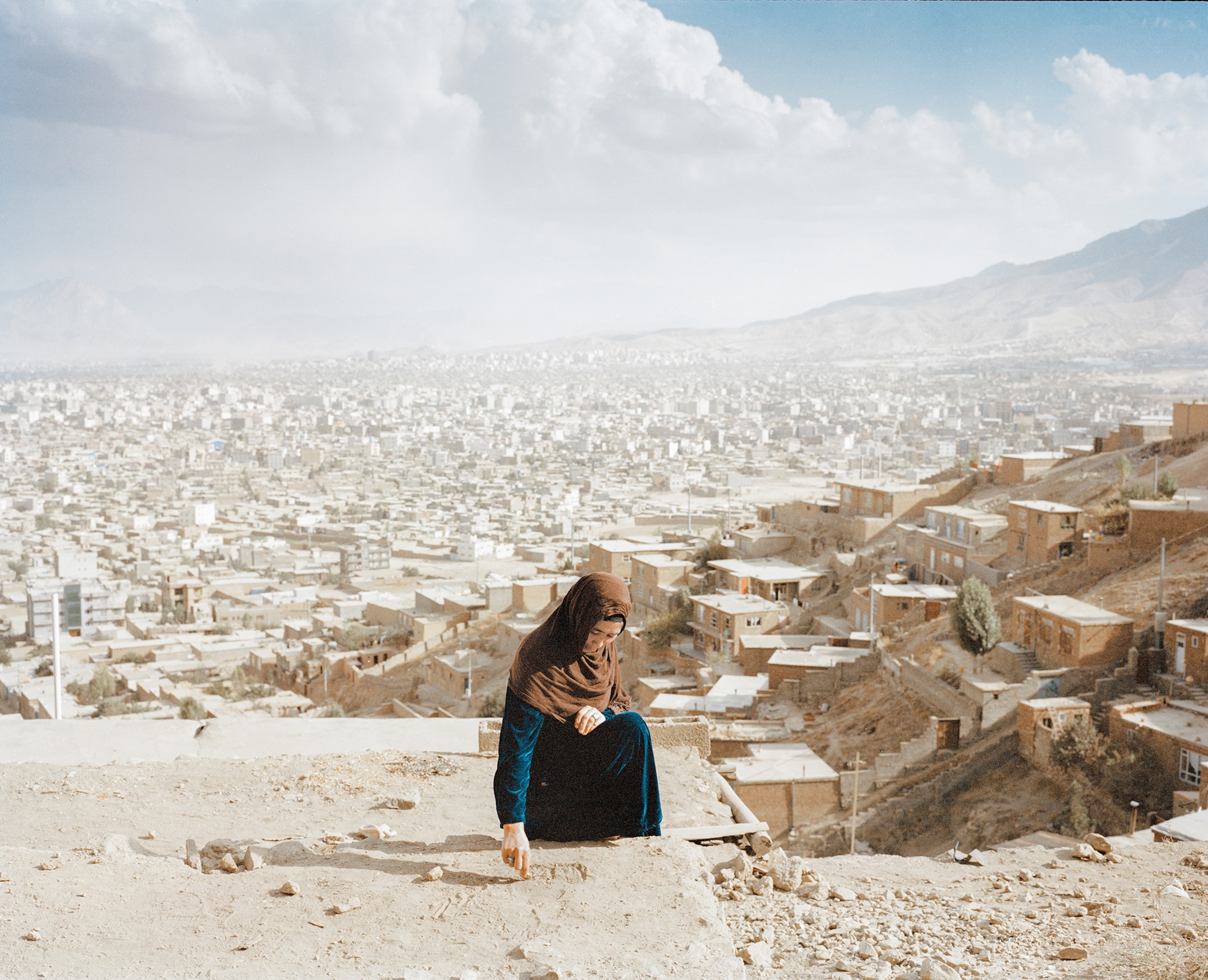 A woman crouches down atop the roof of a home in Kabul, Afghanistan. 