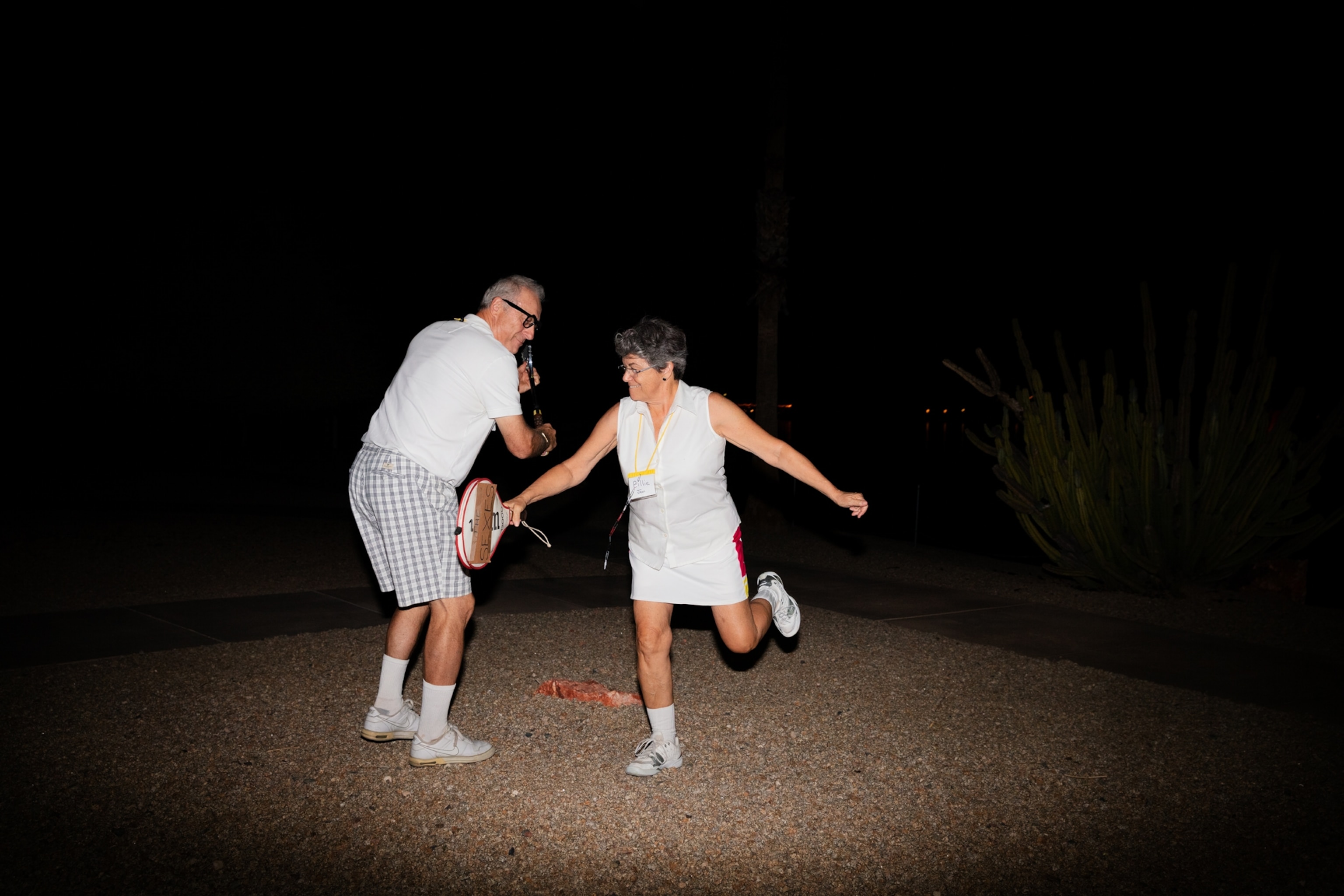 Picture of man and woman in white with tennis rackets.